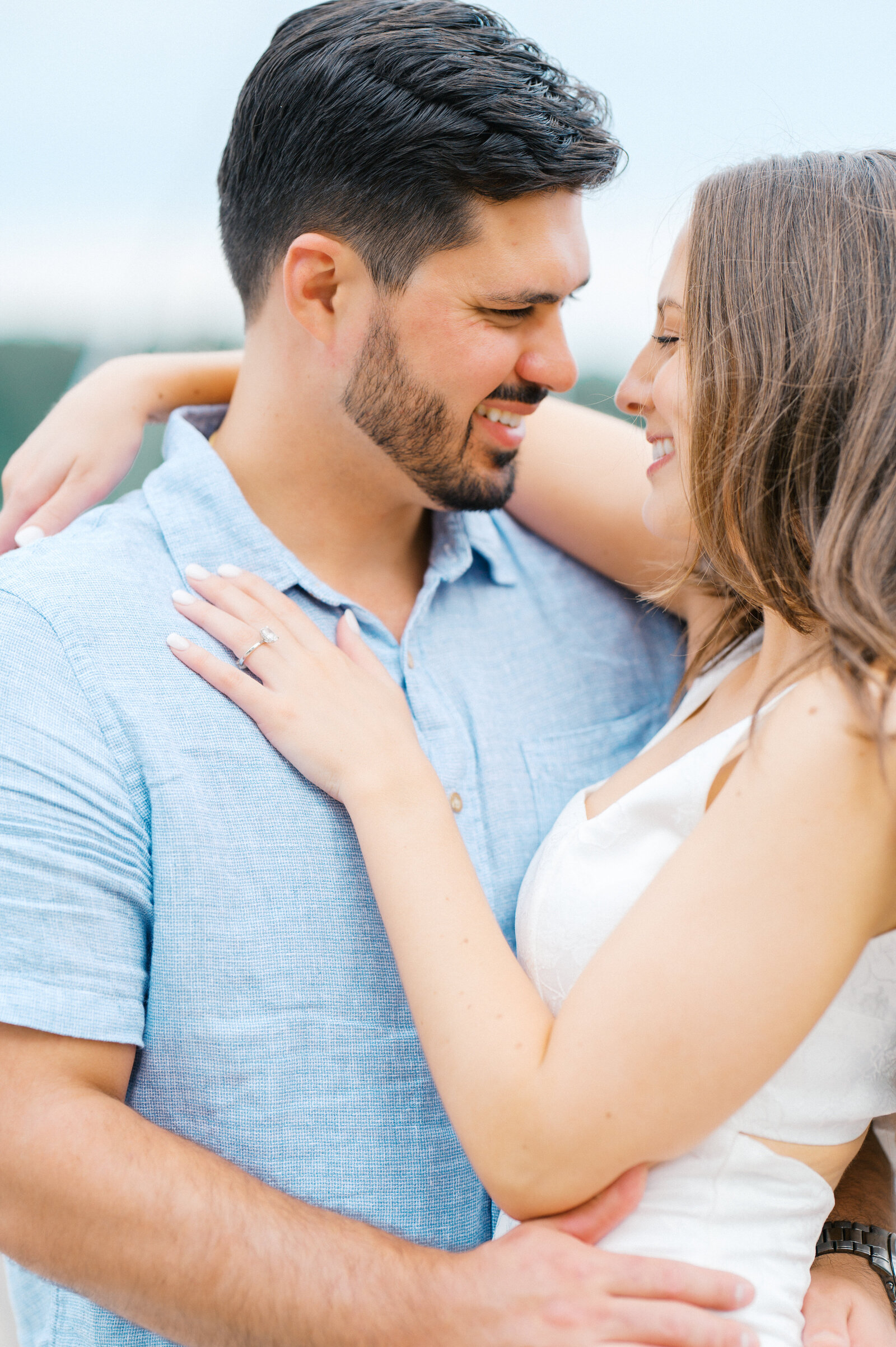 Girl wraps her arm around fiances neck as they stare into each other's eyes on boat engagement session