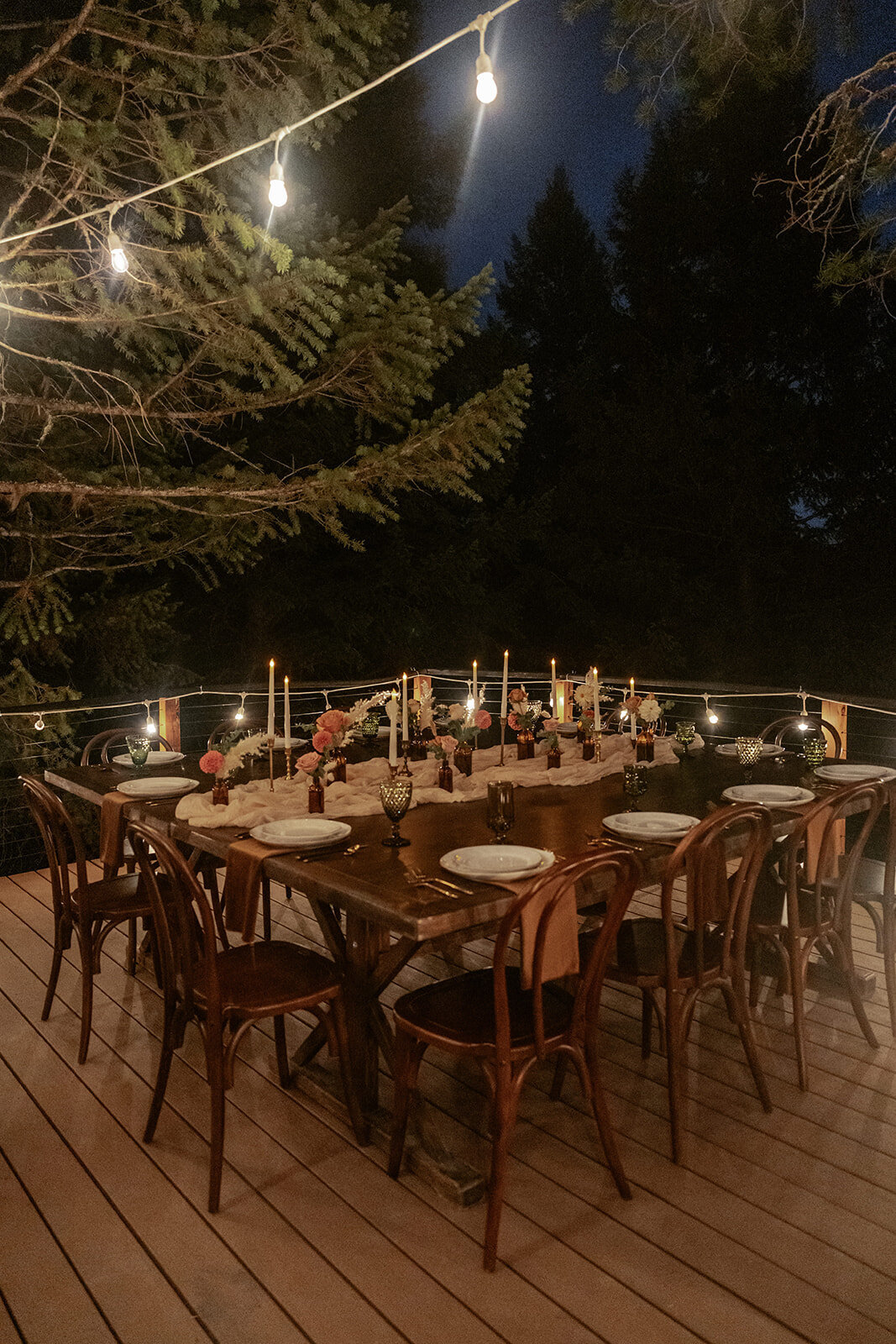 Romantic outdoor dinner table for an intimate elopement, illuminated by candlelight and string lights for a warm, magical evening celebration.