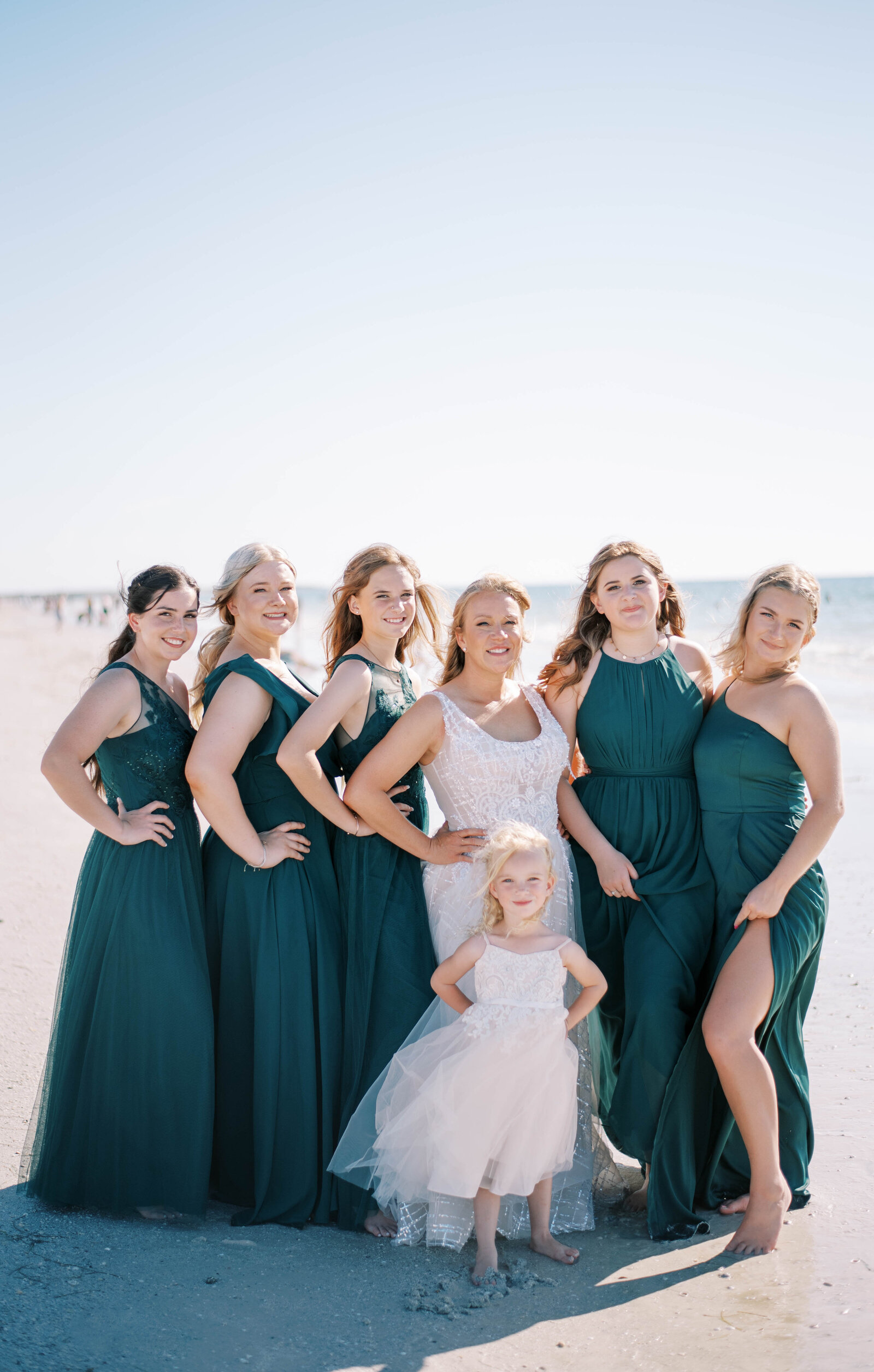 bridal party on beach wearing emerald dresses