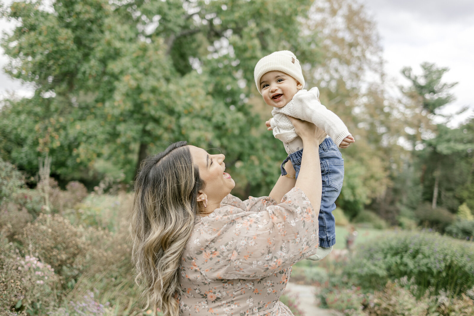 Mom holding baby in the air in a garden