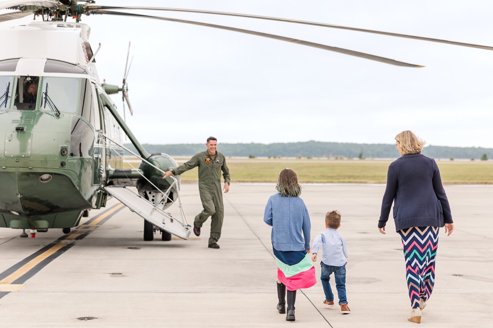 Kids running up to their dad who is walking out of a Marine helicopter