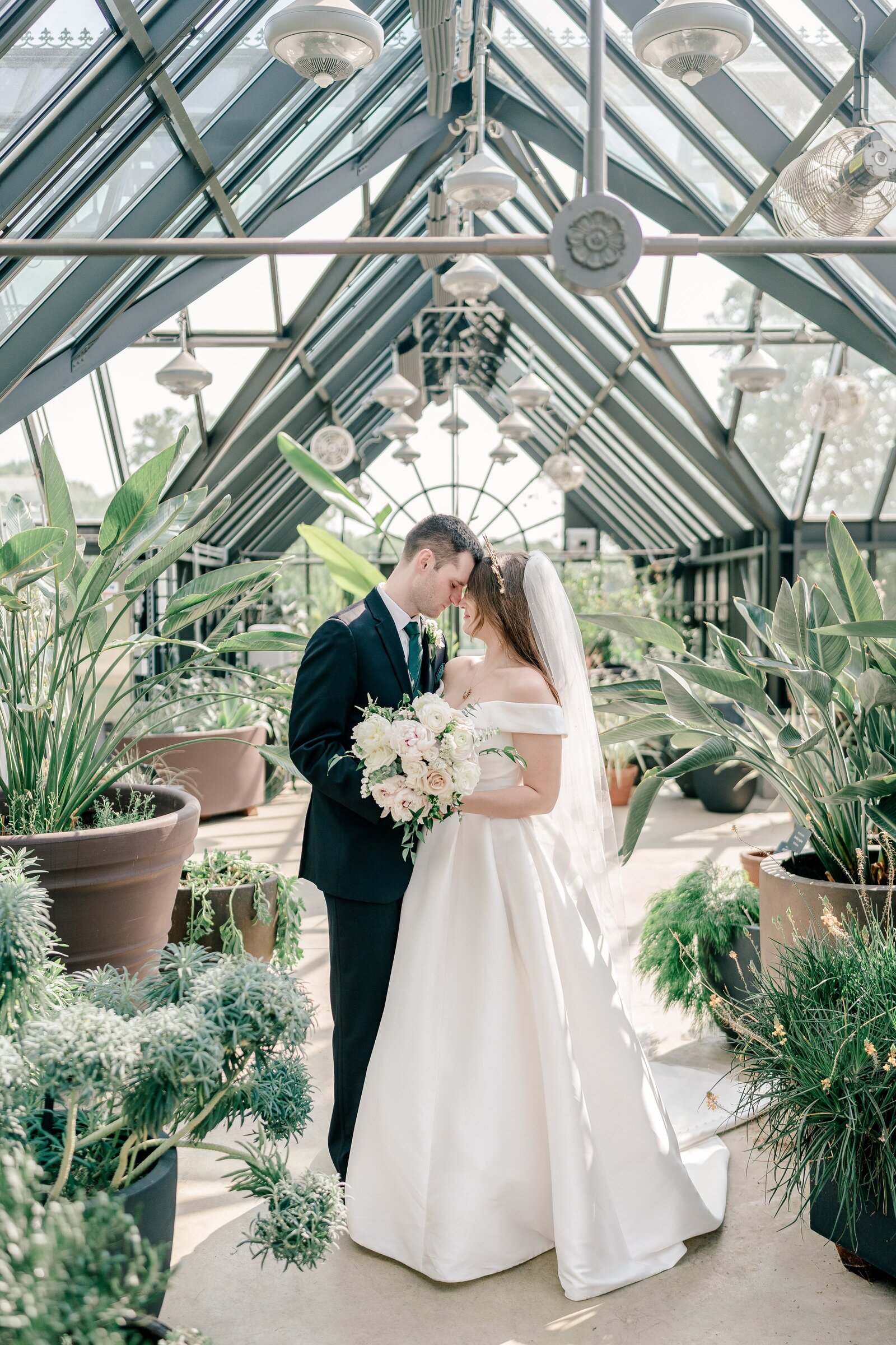 A bride and groom pose for a classic portrait inside the greenhouse during their wedding at Meadowlark Botanical Gardens in Northern Virginia