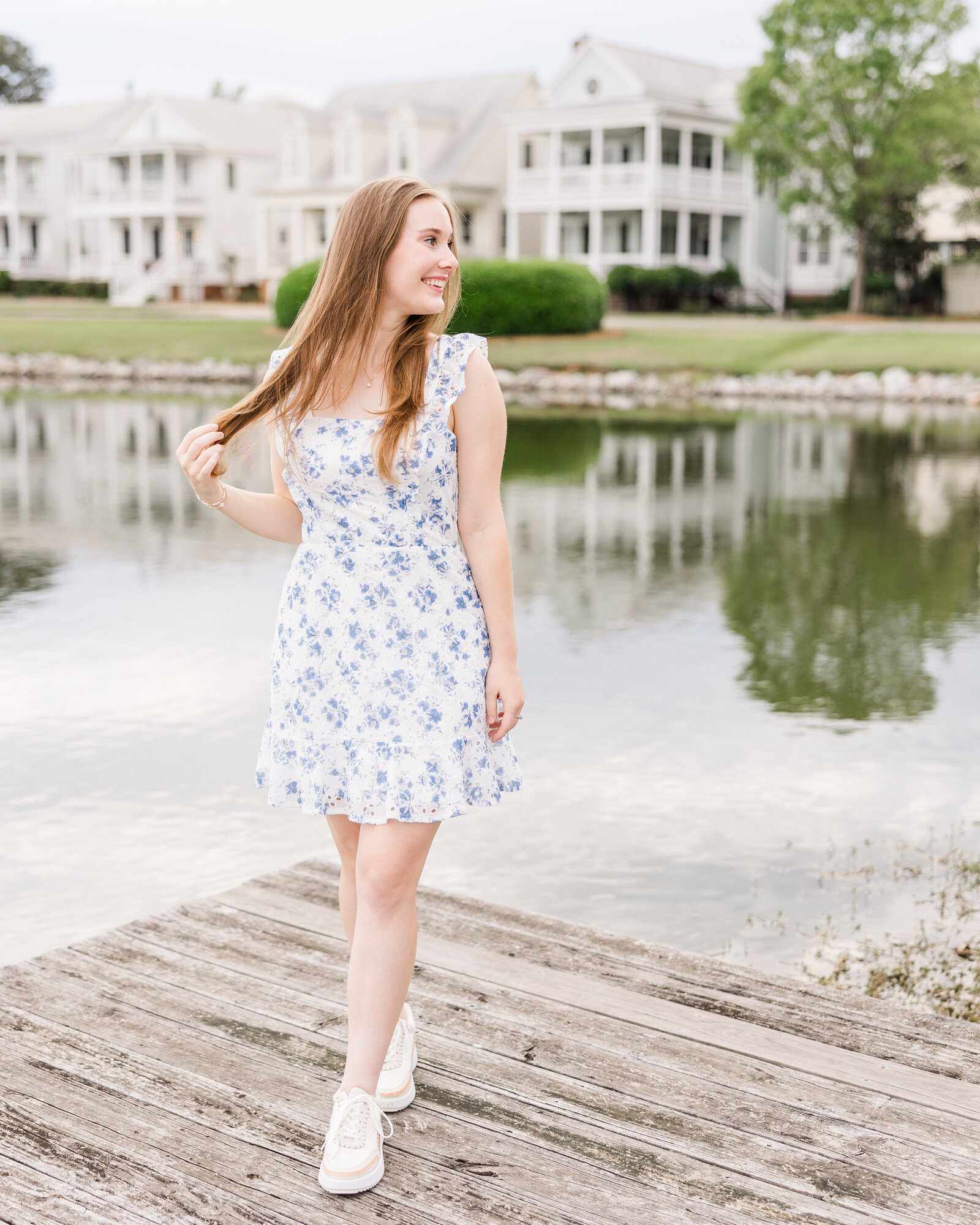 Sophie standing on a lakeside dock wearing a blue floral dress, photographed by Abby Bell Photography, Fine Art Portrait Photographer based in Alabama.