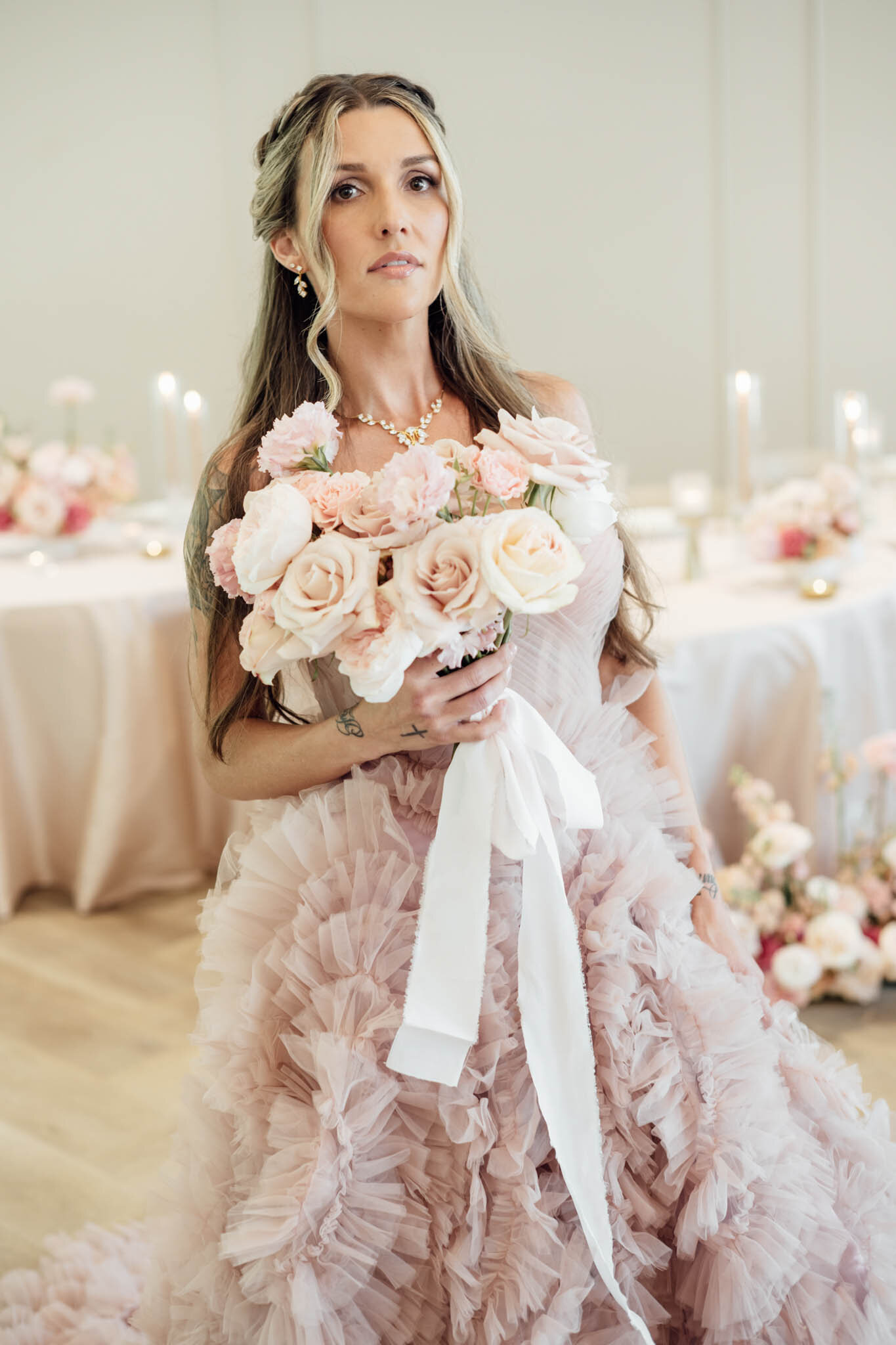 Woman in blush ruffled gown holding soft pink bouquet