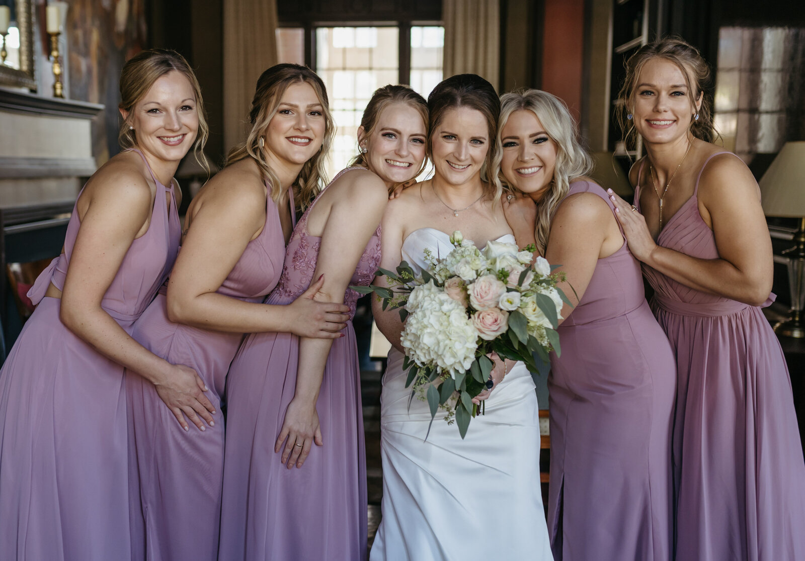 A bride smiles with her bridesmaids in a hotel