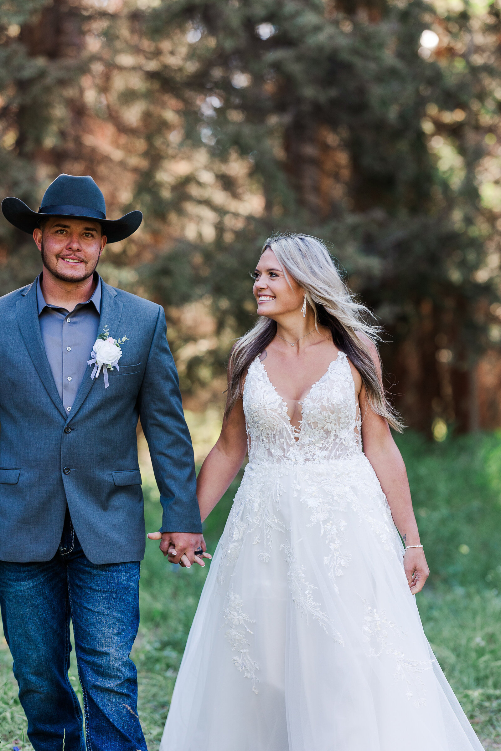 Bride looks over at groom as they walk together hand and hand in Arrowhead