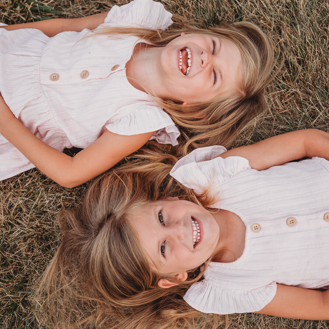 twin girls laughing on grass