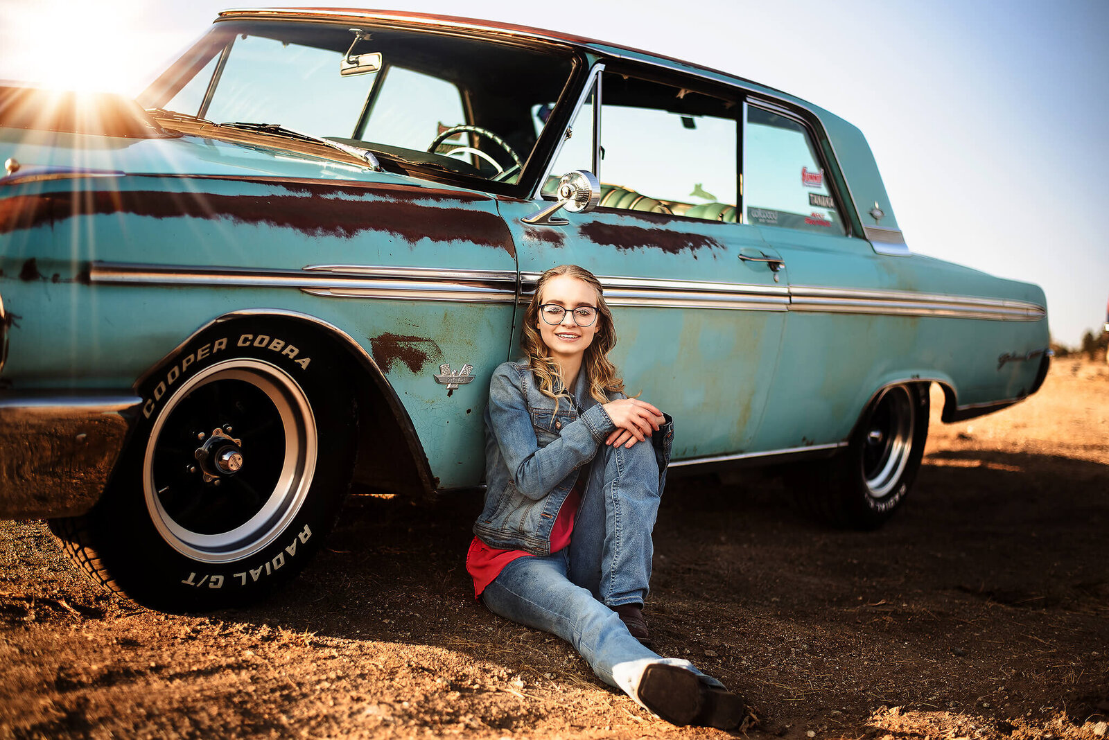 Senior girl wearing blue jeans leaning up against her vintage car near Jackson Wyoming