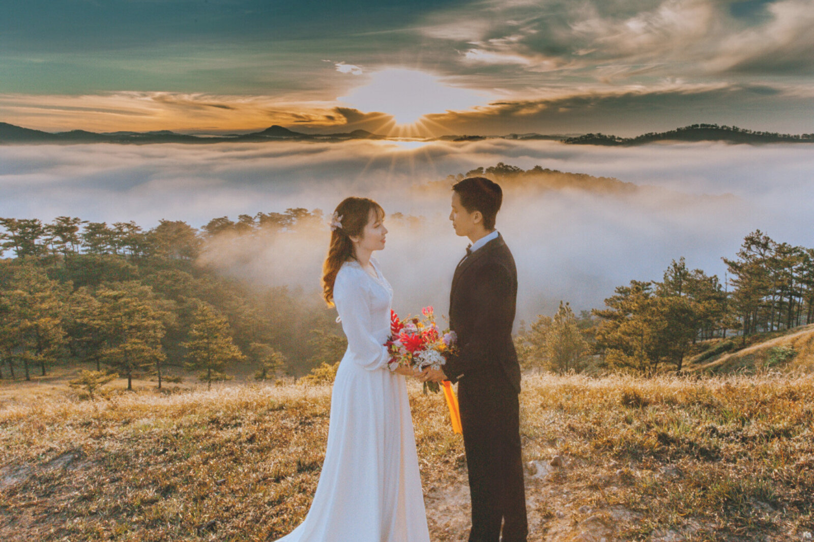 Bride and groom facing each other holding floral bouquet with nature view