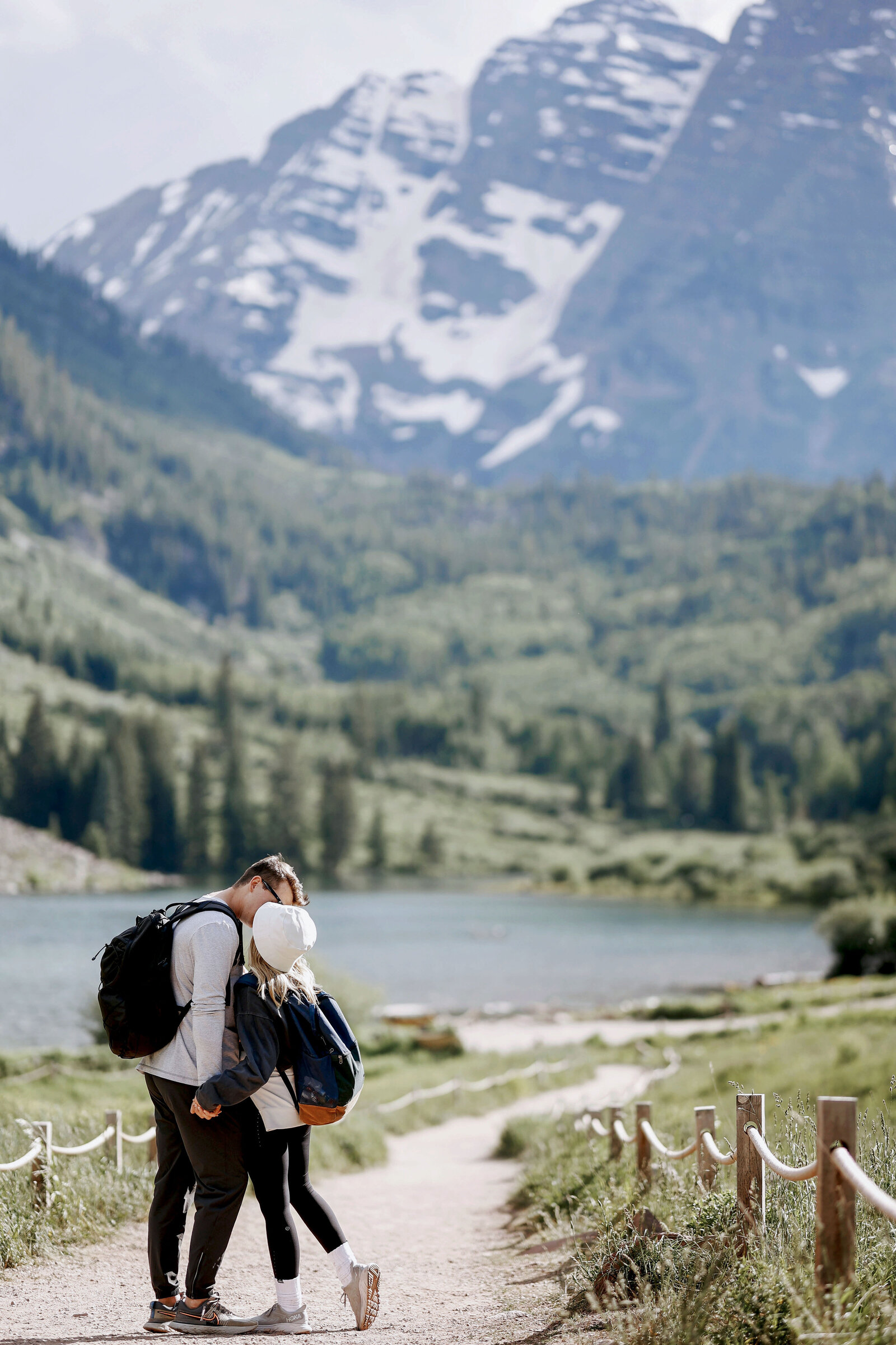 A young couple wearing running shoes and backpacks gets engaged in front of the Maroon Bells in Aspen, Colorado,