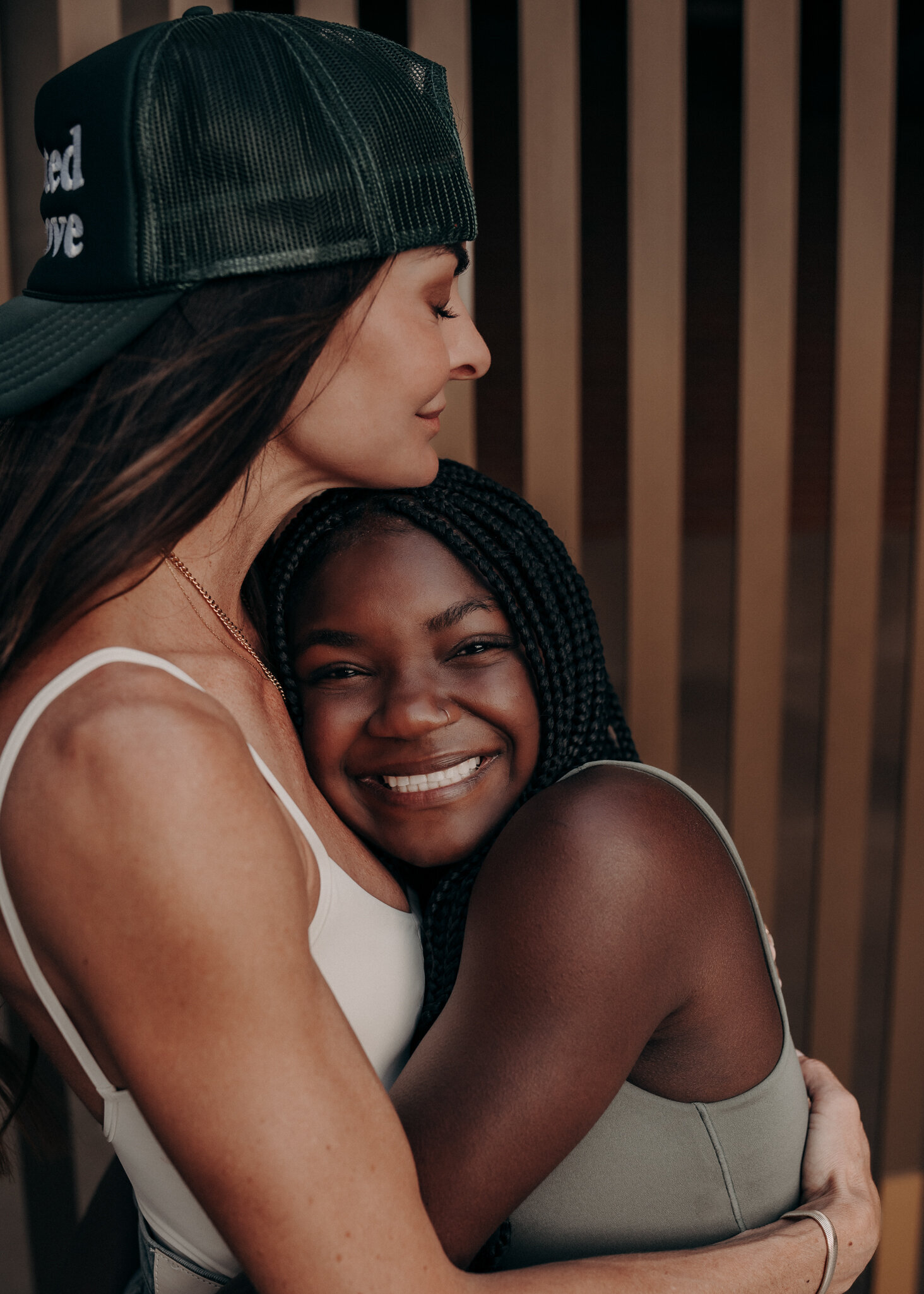 A mother hugged her daughter in a profile position as her daughter stares directly at the audience with a giant smile on her face.