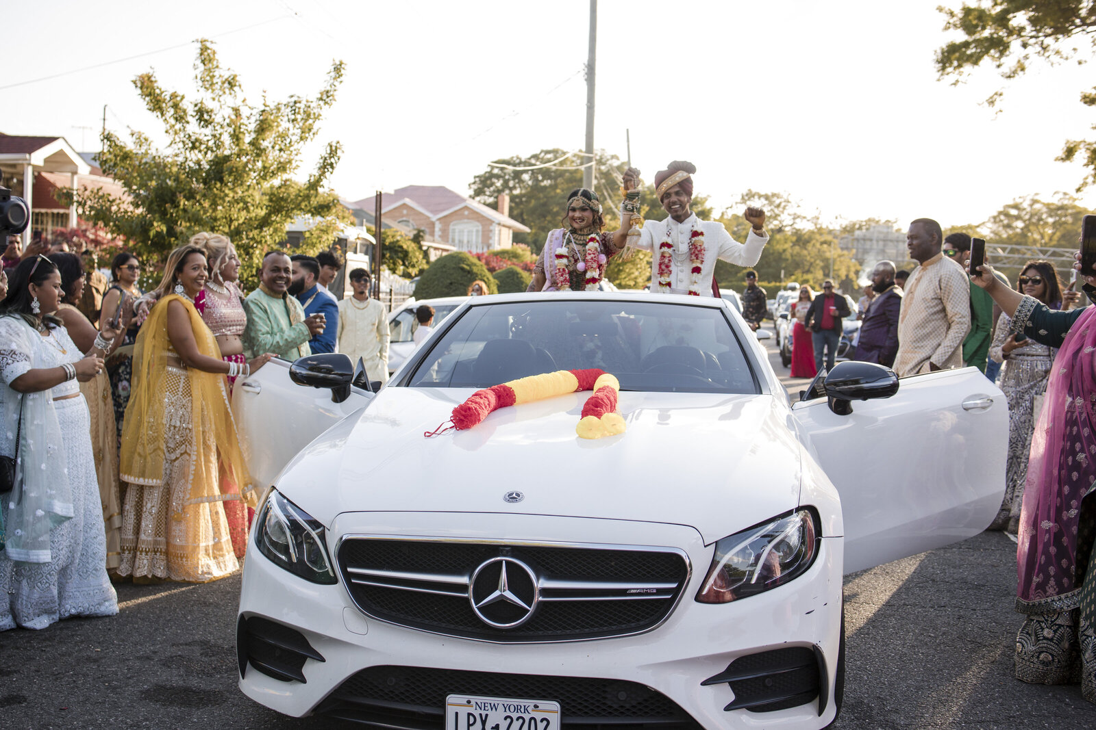 Young Guyanese couple celebrating their Hindu wedding entrance arriving in a white convertable in Queens NY.