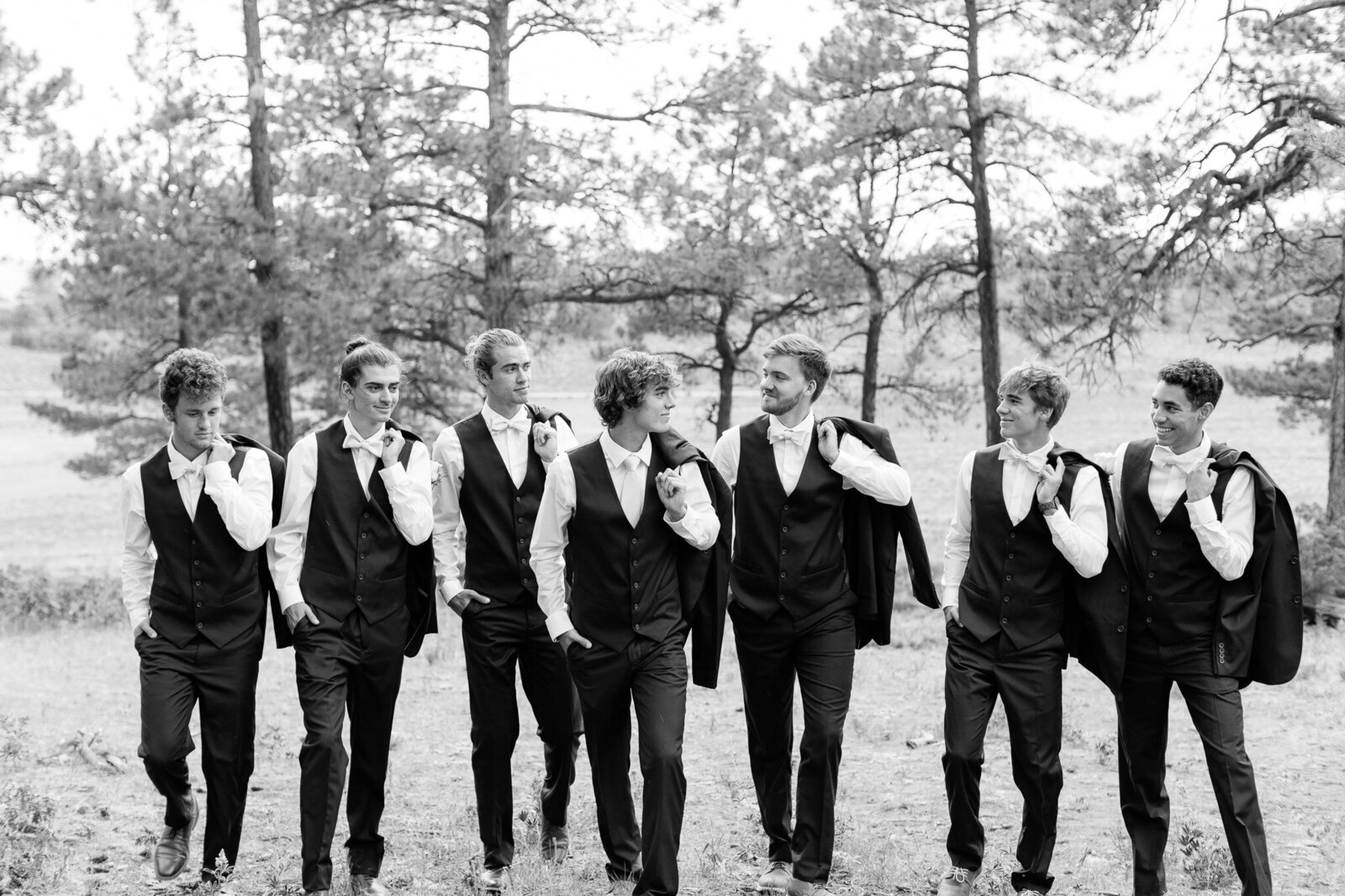 black and white of groomsmen walking jackets over shouldrs
