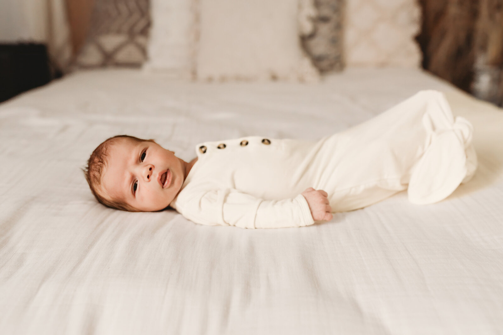 A newborn wiggles during a newborn lifestyle photoshoot with Nikii Pix Photography