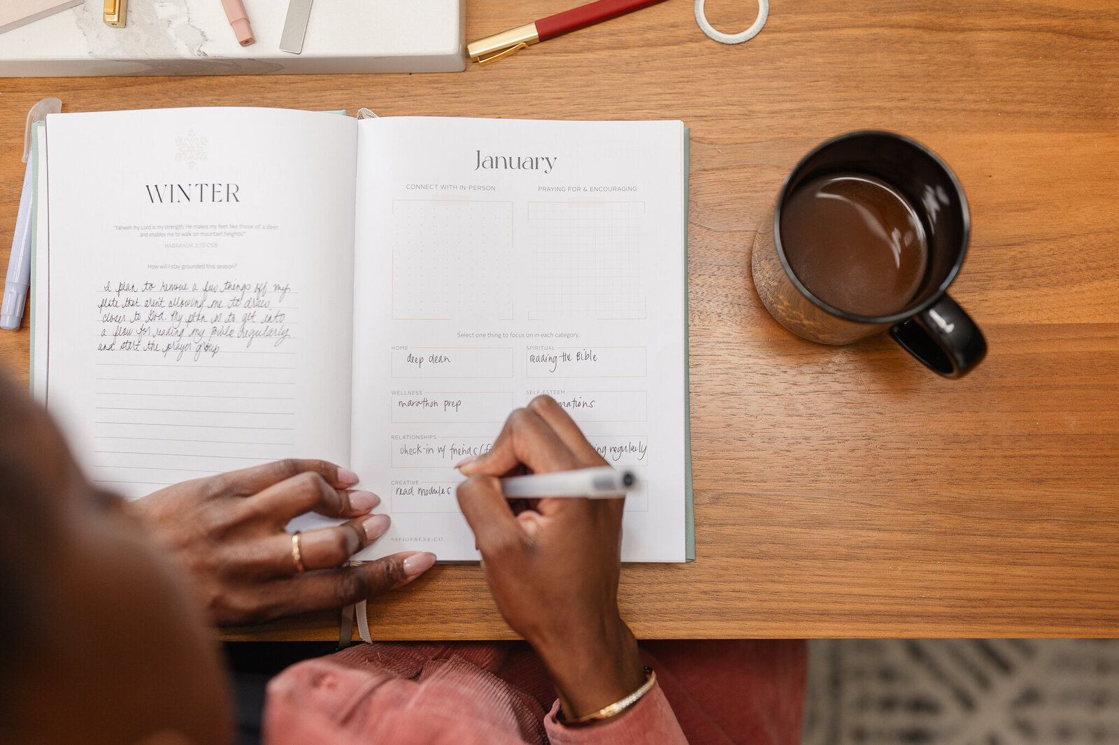 an overhead shot of a woman writing in her planner