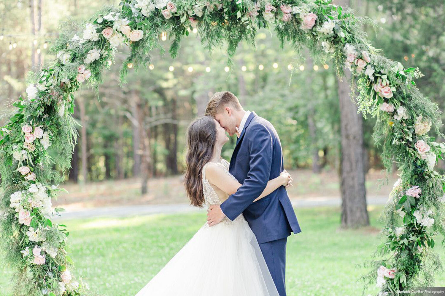 Bride and groom sharing a moment under a floral arch outdoors