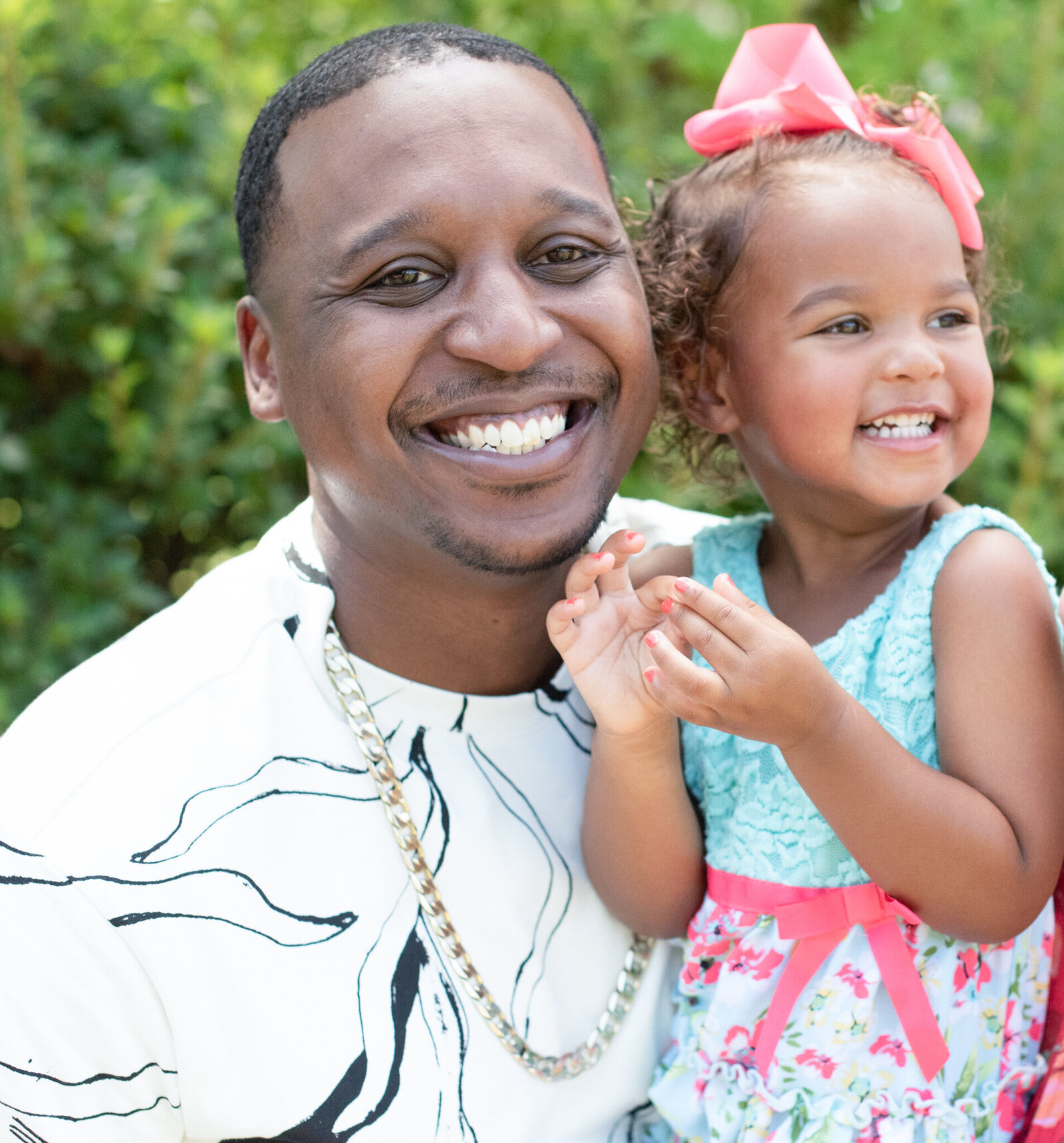 a father holding his daughter. both are smiling photographed by Millz Photography in Greenville, SC