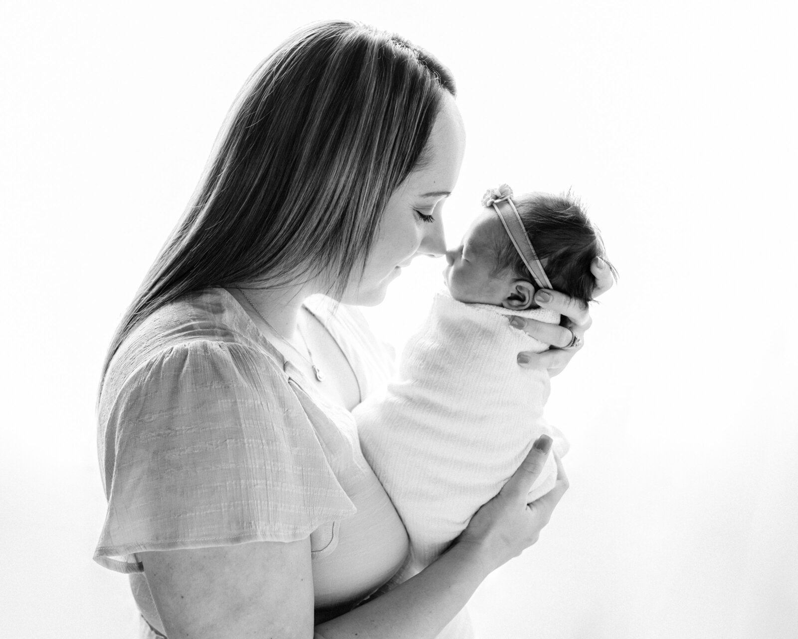 mom touching newborn baby girl's nose for studio portrait