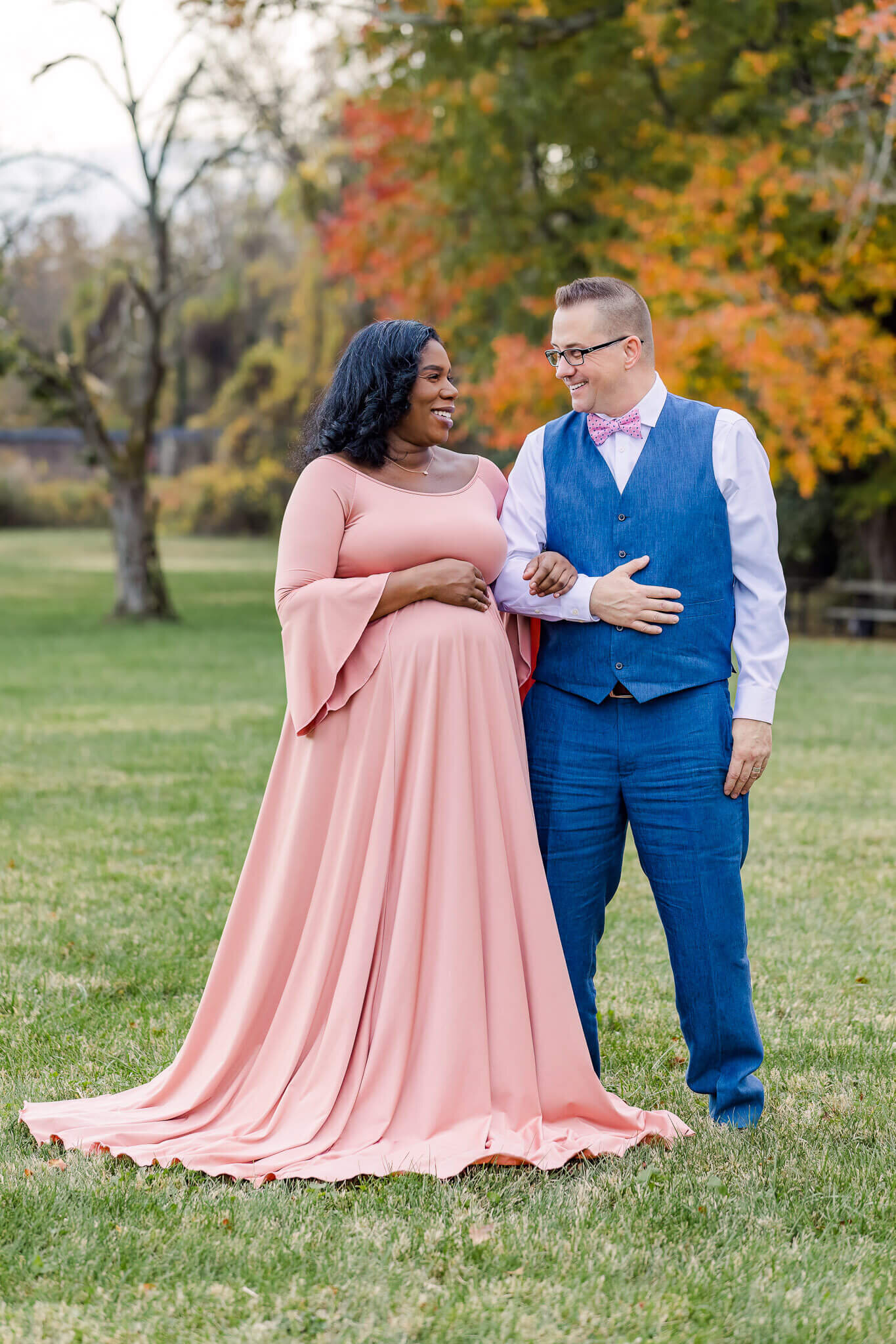 A beautiful expecting couple posing in a field.