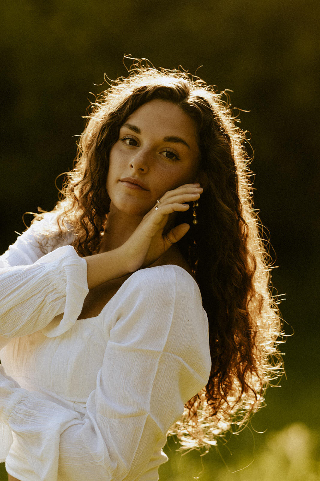 A senior girl's ethereal beauty shines in the soft, golden light of a sun-kissed afternoon, documented by a creative West Michigan senior photographer.