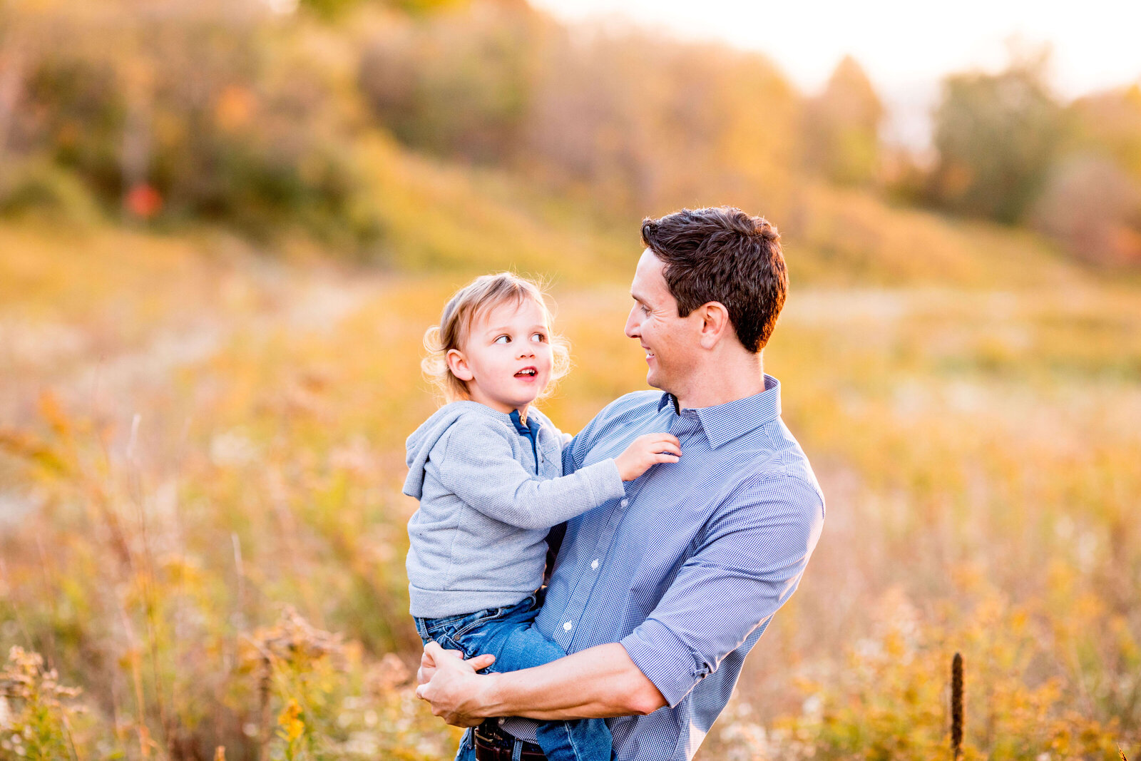 Young son makes father laugh during family photo session near London Ontario