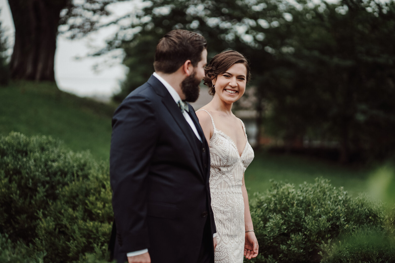 A bride and groom walk down a brick pathway and smile at each other