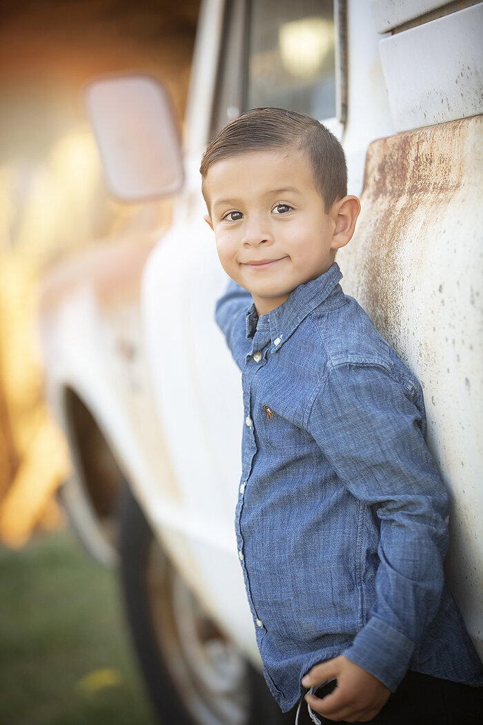 Young boy posing with old ford pick-up truck during family photo session.