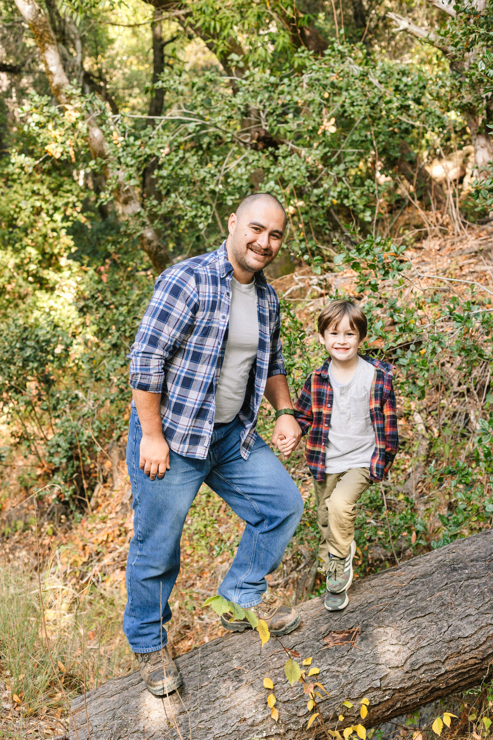 A family of 3 poses for photos in a forest in Santa Cruz, Ca.