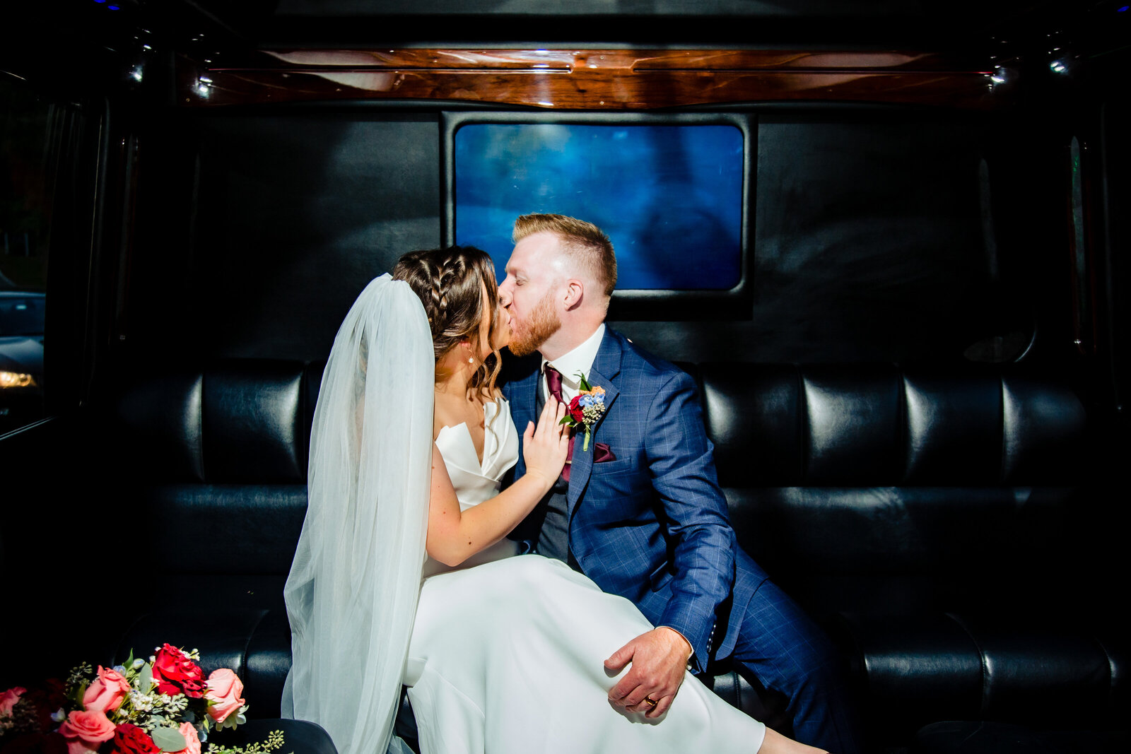 Bride and groom kiss in limousine