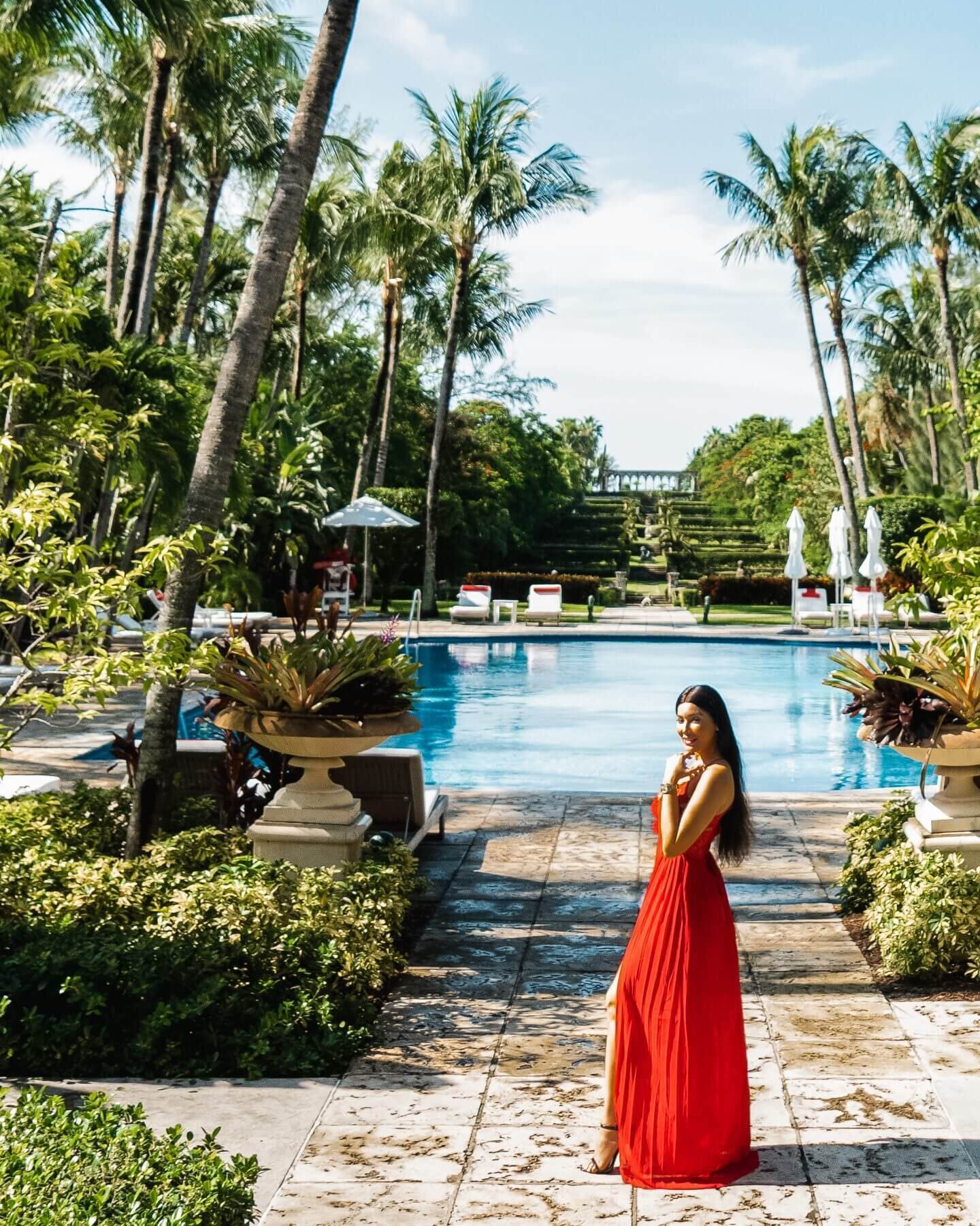 Isabella standing in red dress by pool - luxury travel blogger