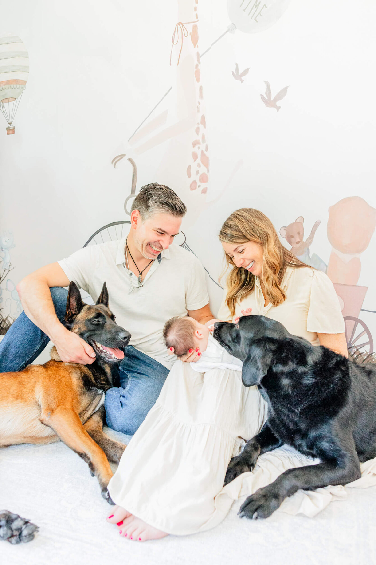 Mom and dad laugh with their dogs and baby