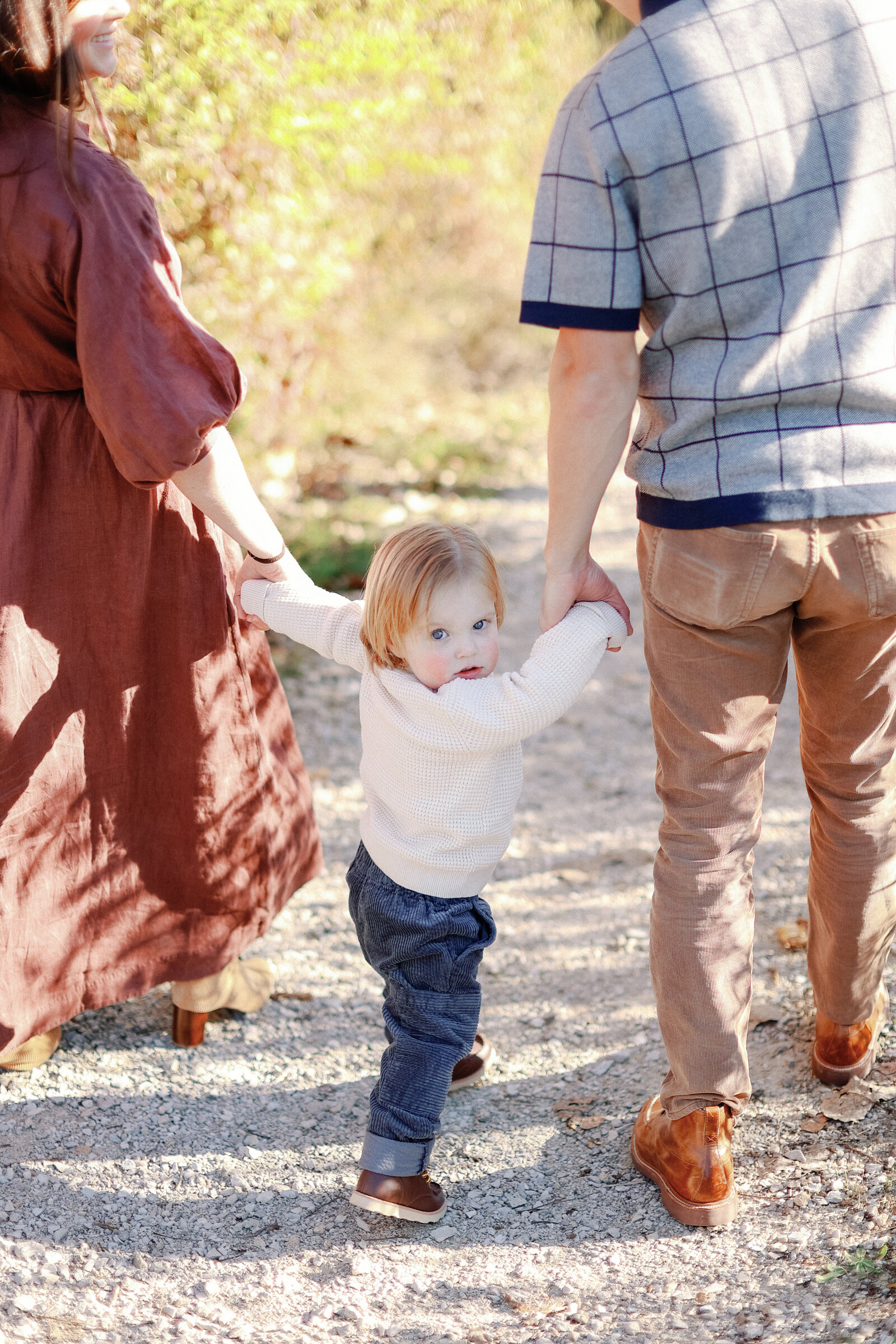 little boy walking with family and looking back