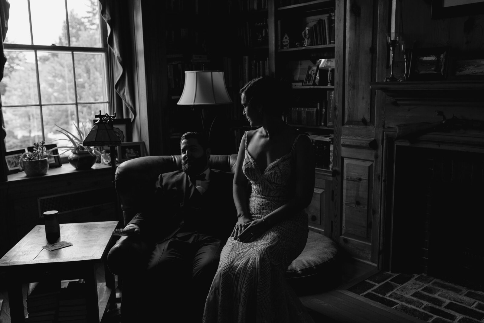 A bride and groom sit together in a dark library