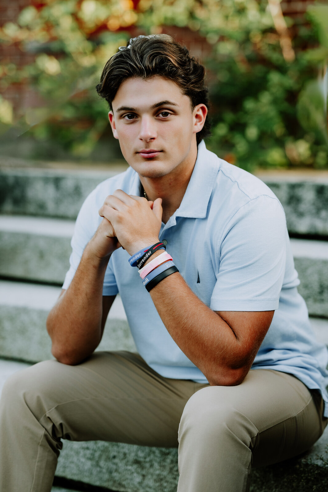 Boy sitting with his hands folded under his chin looking at  the camera. 