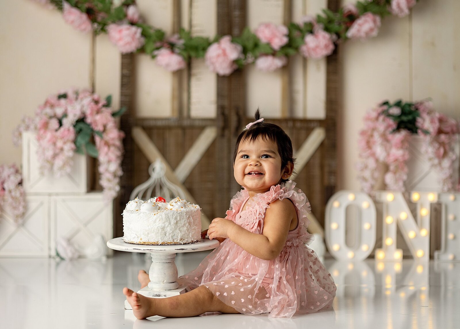 baby girl smiling with her cake smash