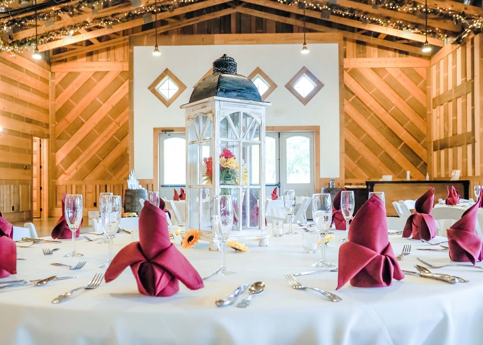 A rustic dessert table with a tiered wedding cake, cupcakes, and fall-inspired decor, set in a charming barn venue during a Boone, NC wedding, blending rustic elegance and cozy warmth.