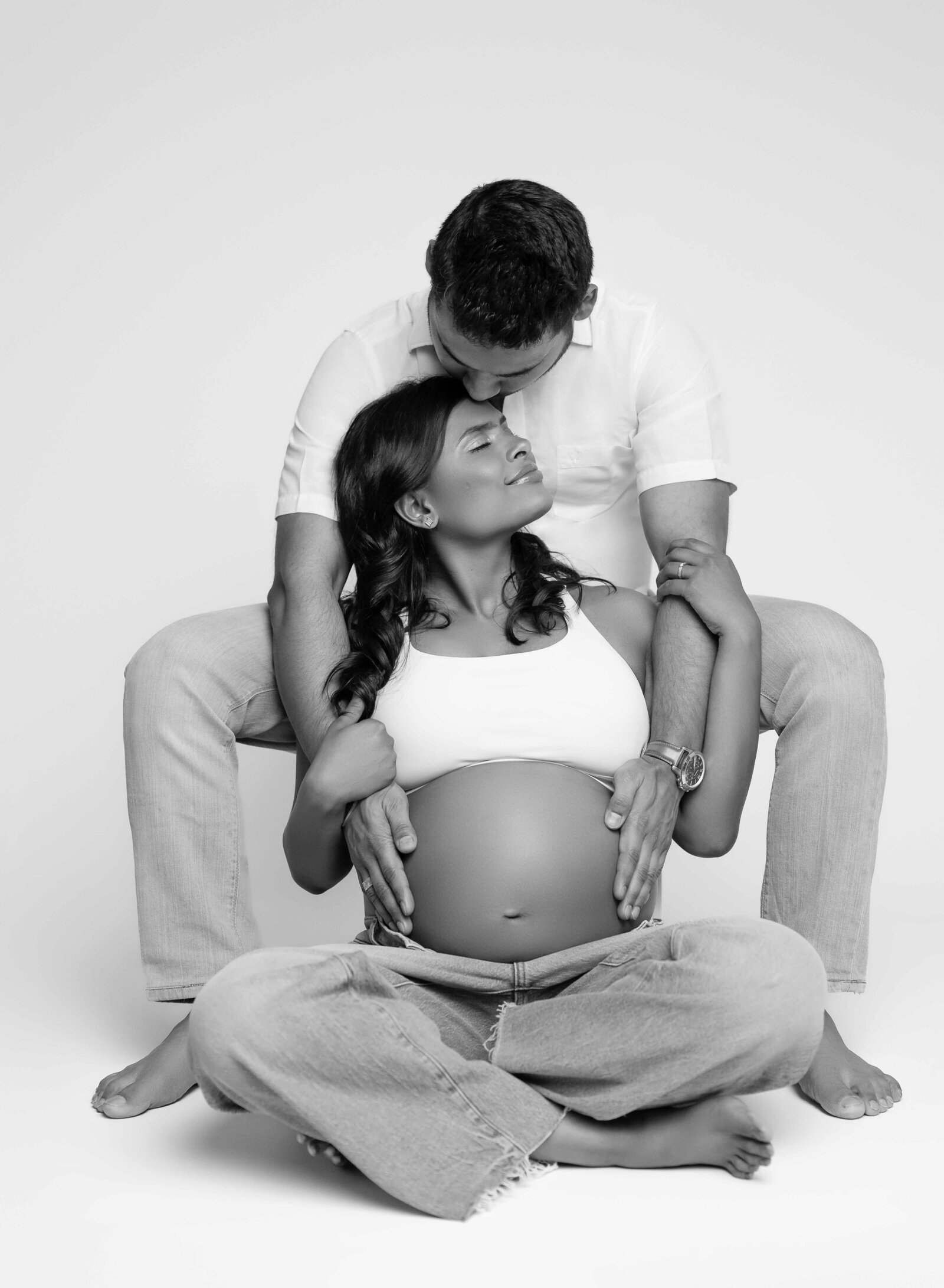 Casual pregnancy photo with Mom and dad in jeans, holding baby bump. Pregnancy photo by Jenni Nikki Photography at Atlanta maternity photo studio.