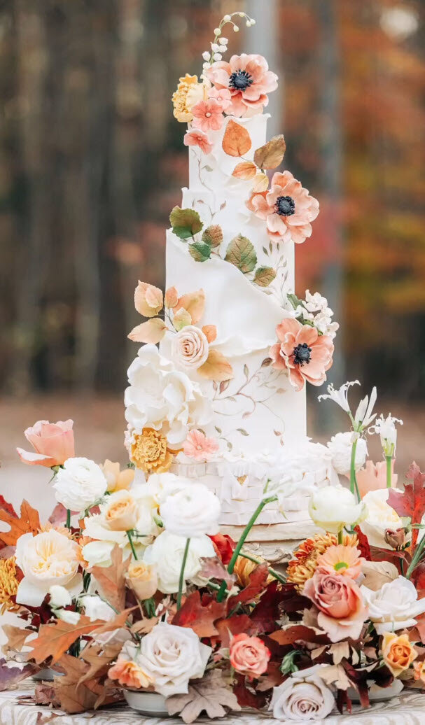 Beautiful 4-Tier Fall-Themed, Bespoke, Luxury Wedding Cake by Artsy Cakesy with fall leaves, pale roses, peach anemone, and white lily of the valley, with hand-painted vines and curled-paper fondant design