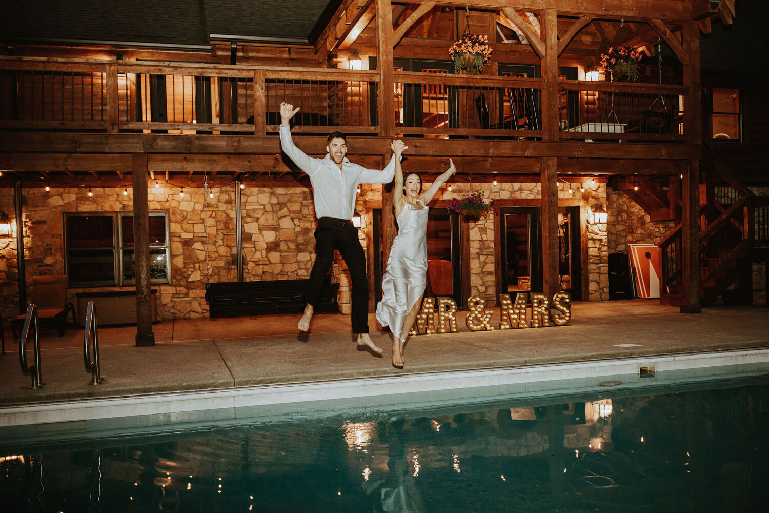 Bride and groom in their wedding attire about to jump to the pool