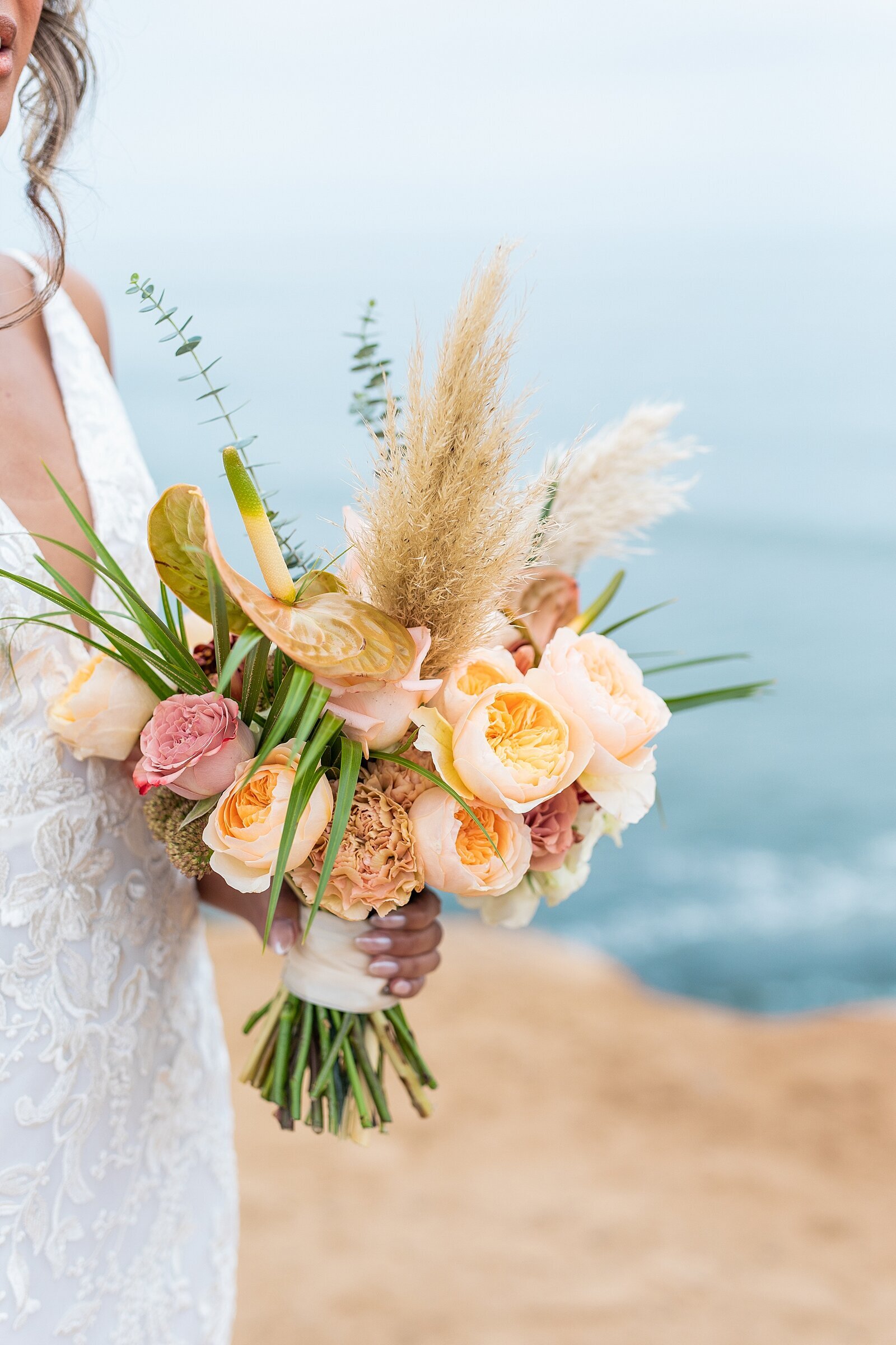 Bride holding boho bouquet at Sunset Cliffs for wedding ceremony.