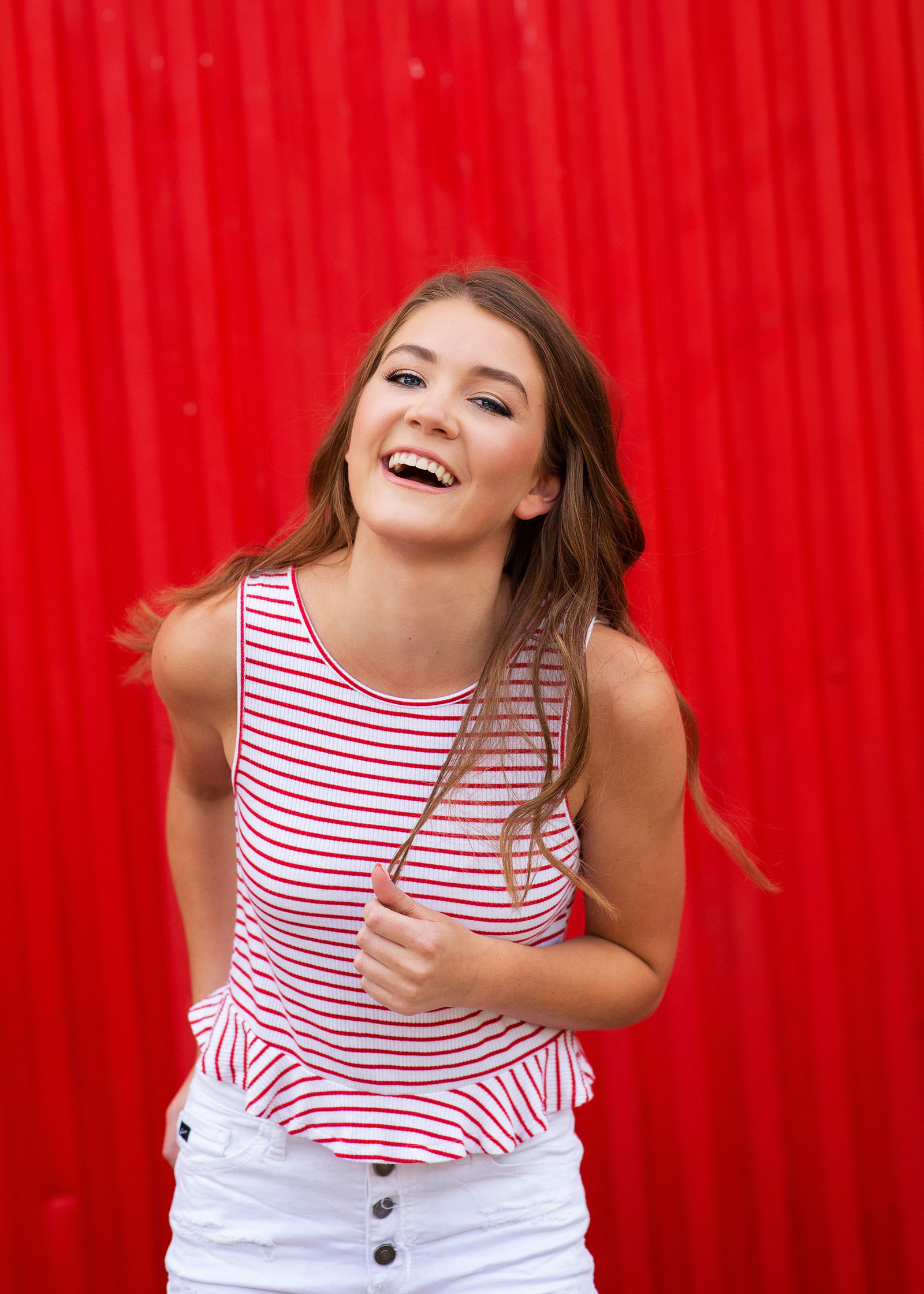 senior giggling in front of red wall