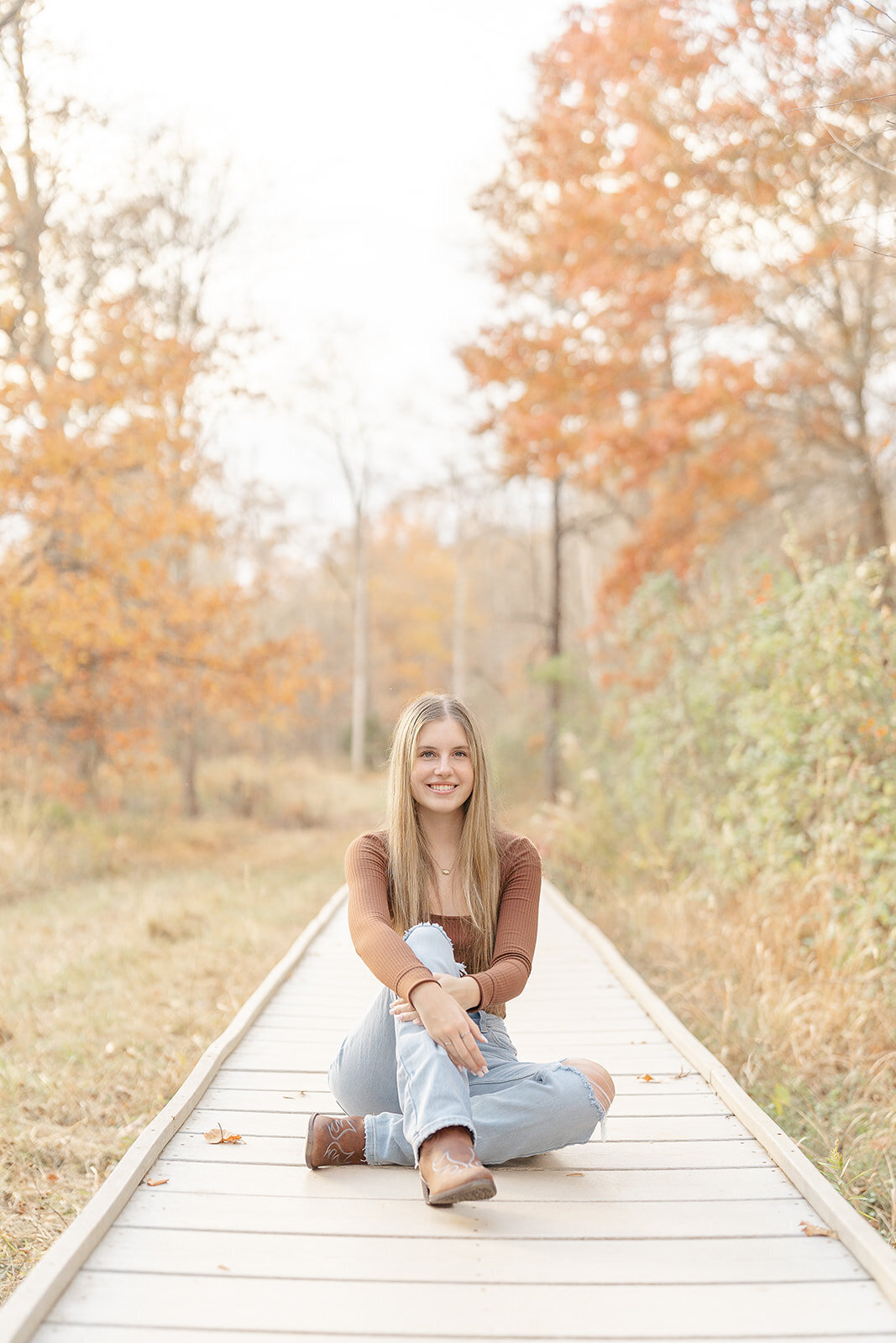 girl sitting on a bridge during fall senior picture in Alexandria, VA