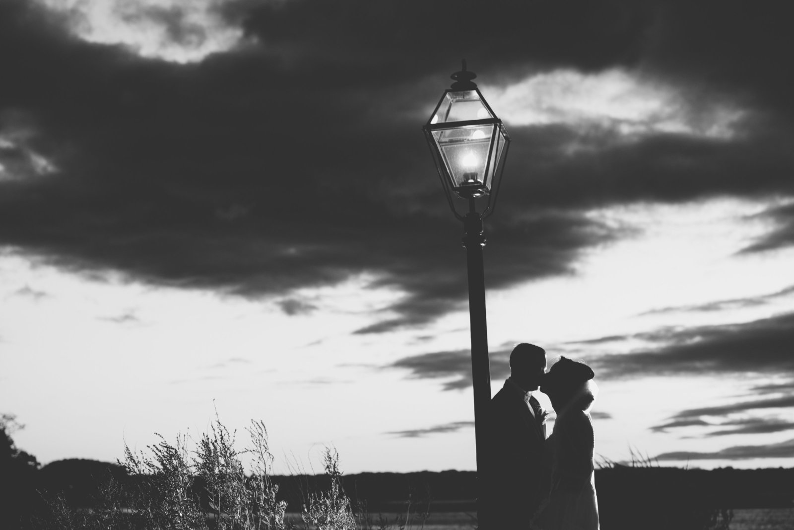 black and white photo of bride and groom kissing outside wedding at Three Village Inn