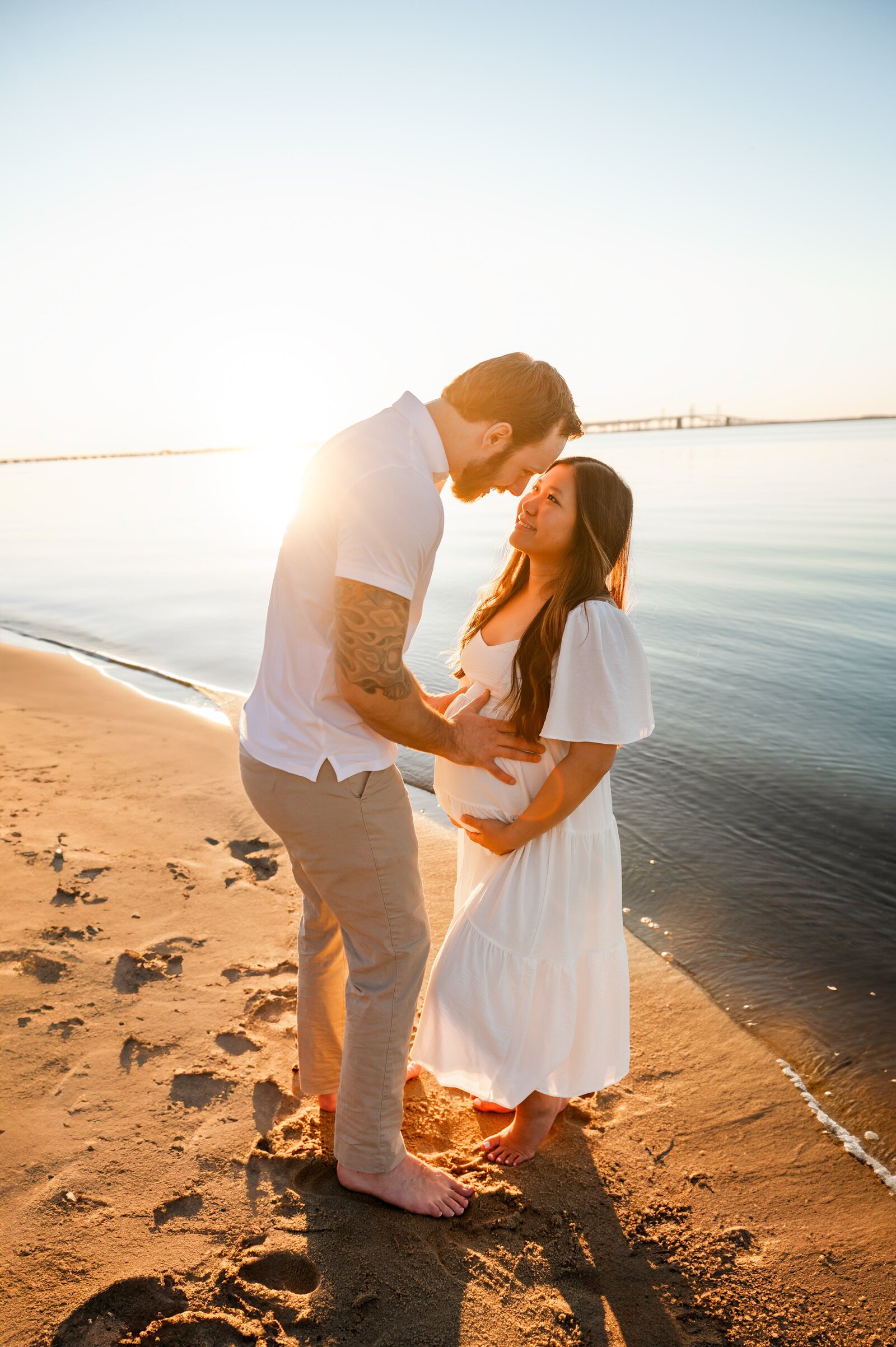 husband holding wife pregnant belly getting ready to give her a kiss