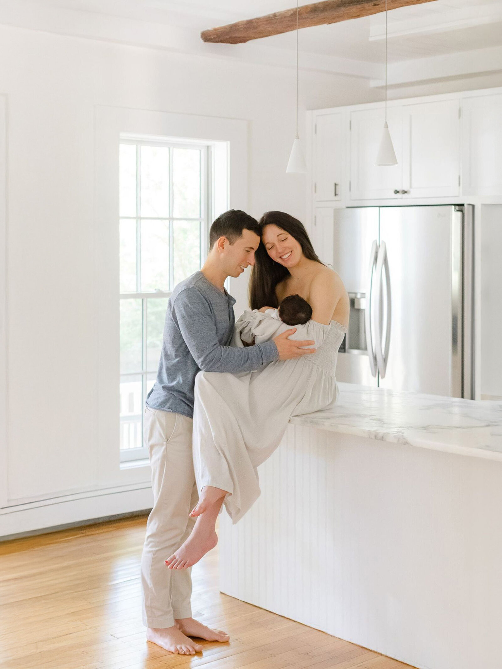 cute boston couple holds newborn in beautiful, bright kitchen