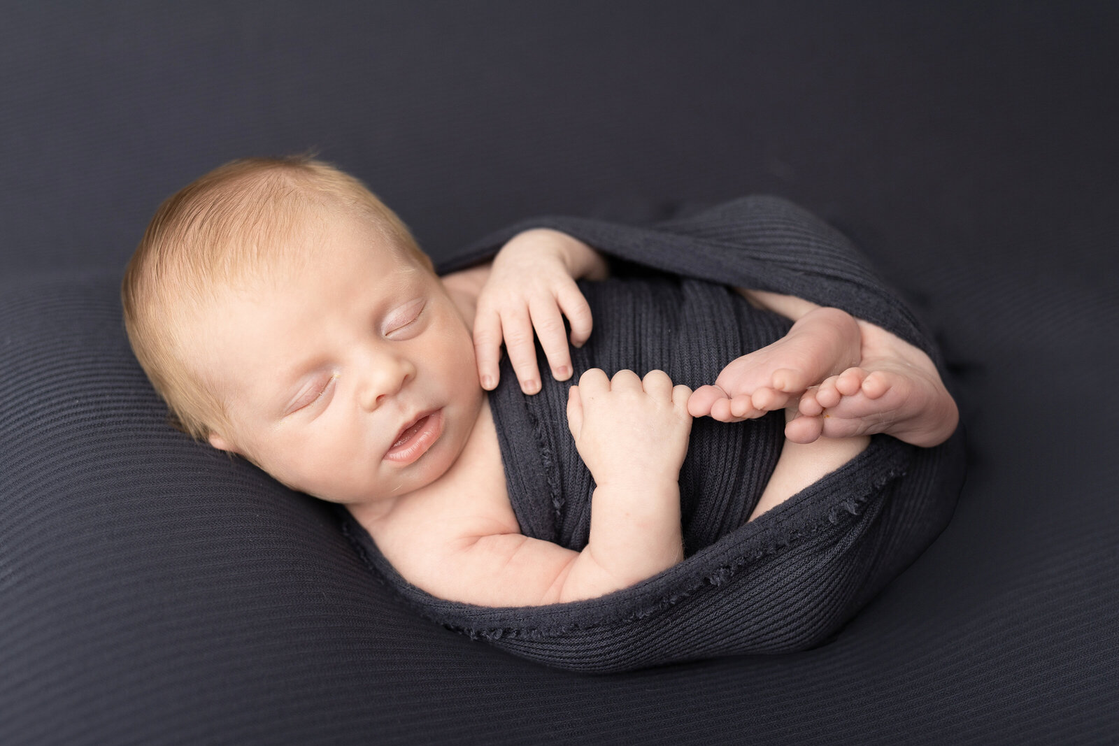 newborn boy in dark blue wrap