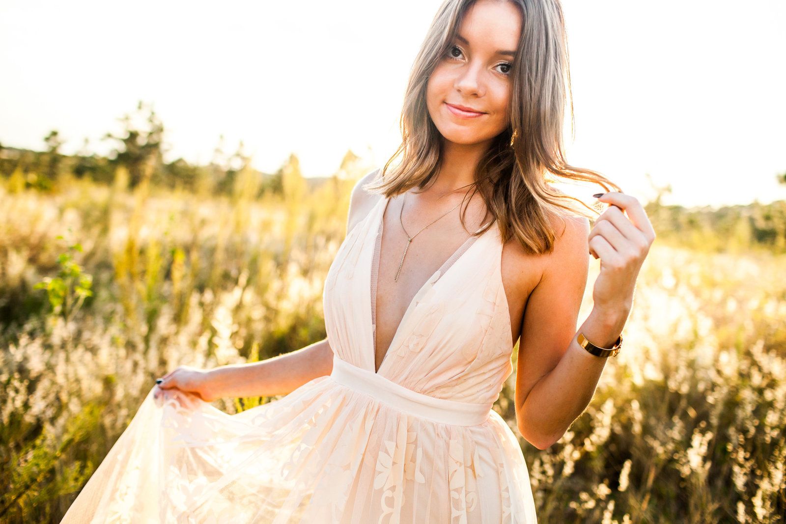 Boho themed senior pictures in field of flowers at sunset