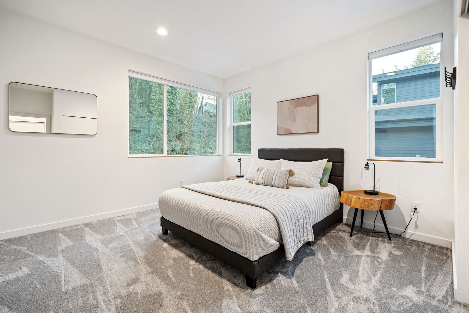 A cozy modern bedroom with a grey upholstered bed and wooden side tables