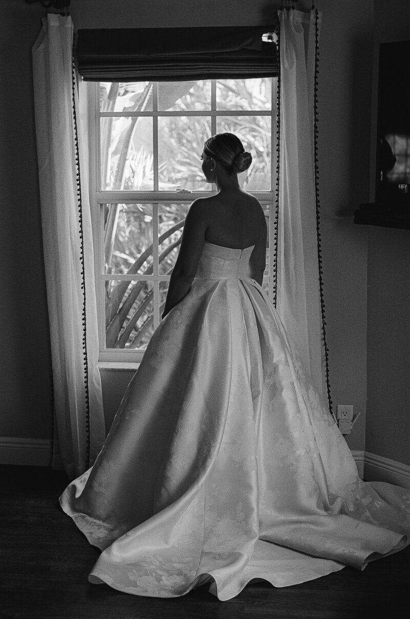 bride photographed looking out of window at fort myers wedding venue in florida