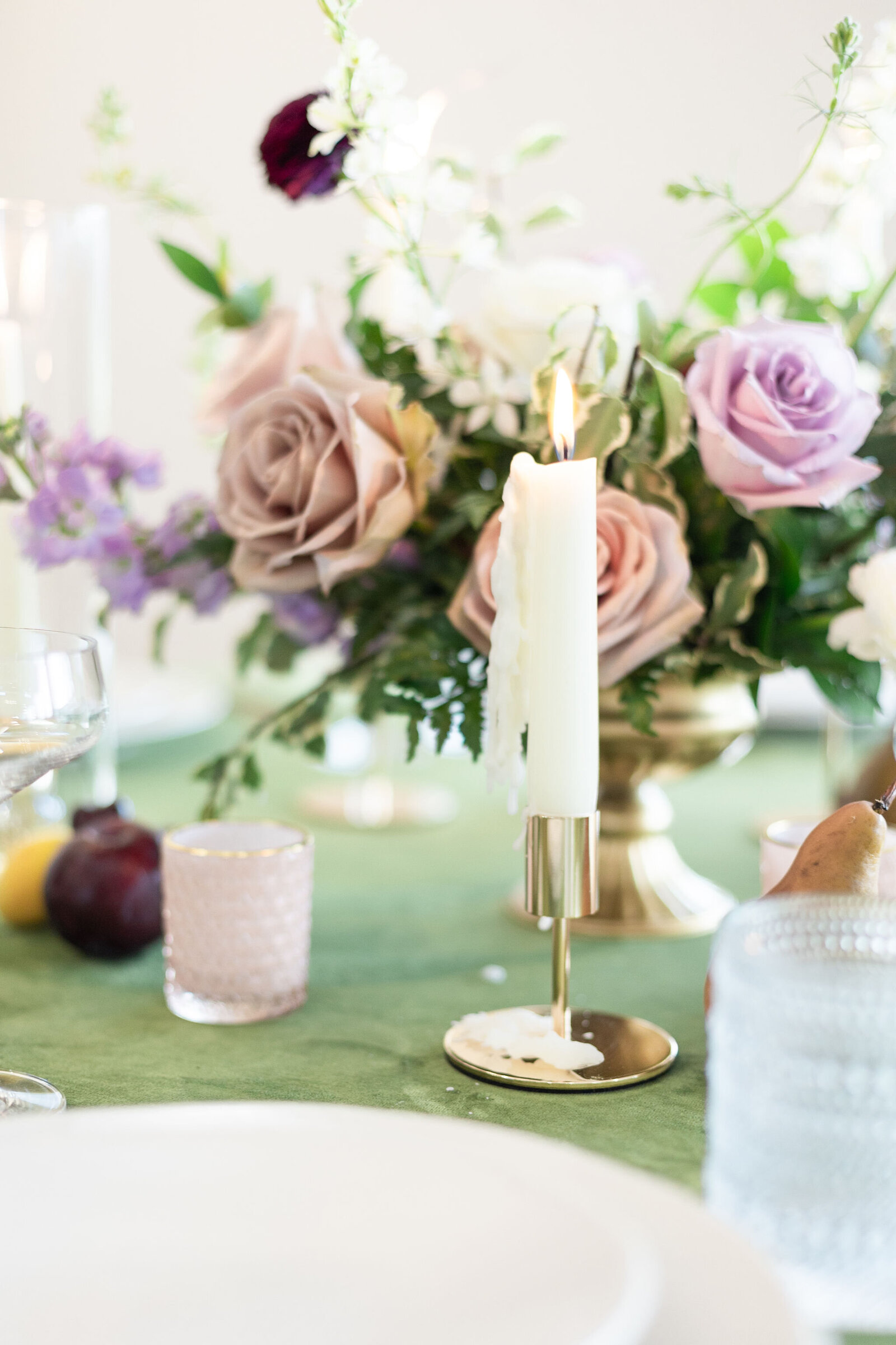 Wedding decor with blush roses, greenery, and taper candles on a green linen table at Willow and Stone Events in Mocksville, NC.